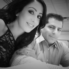 A woman and a man sit close together, smiling at the camera, in a black-and-white photo.
