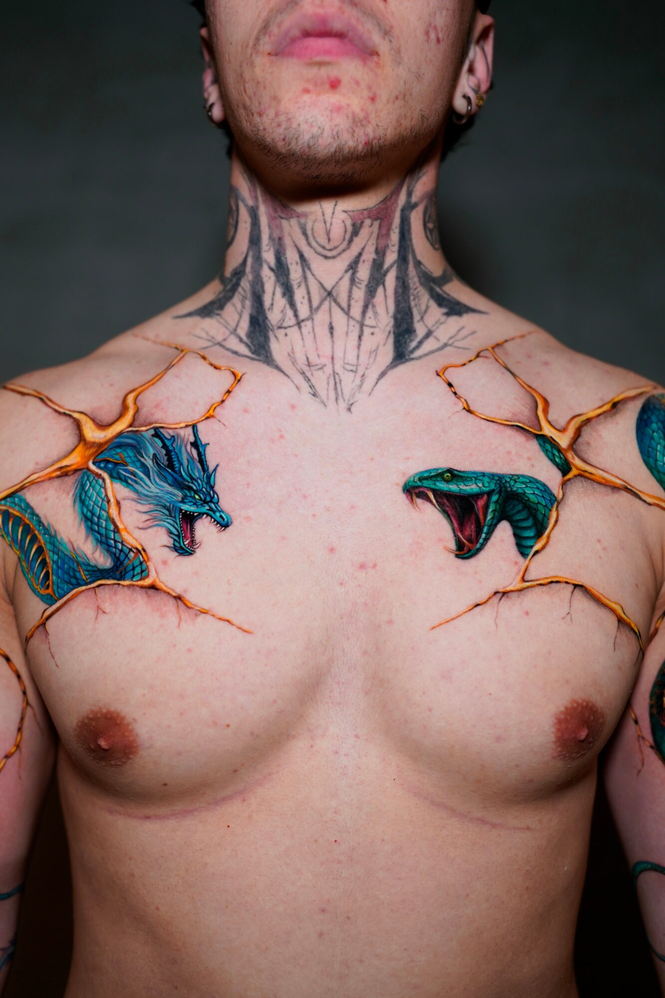 Person with tattoos on neck and chest, including a tiger and a panther, with a dark background.