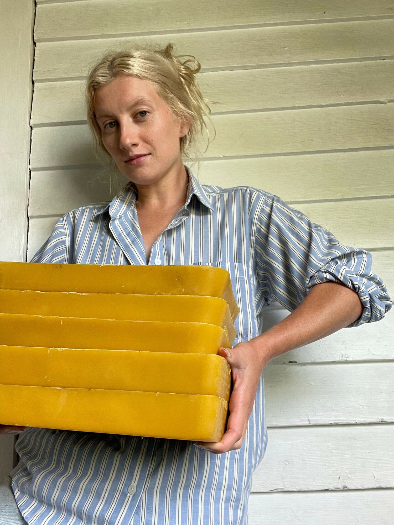 Woman lying on bed holding a yellow object, with a wooden wall background.