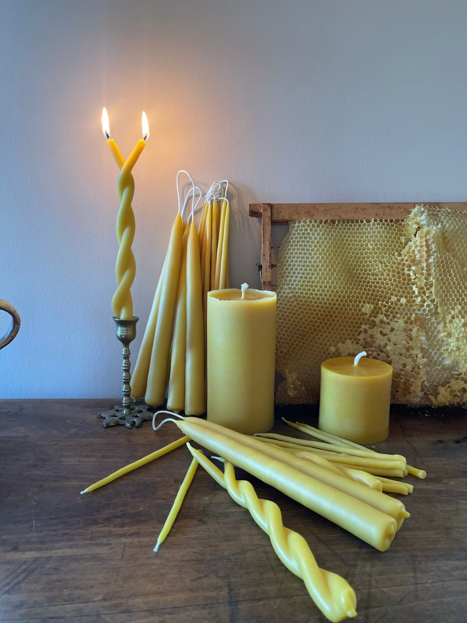 Candles, candles sticks, and a decorative frame on a wooden surface with a plain background.