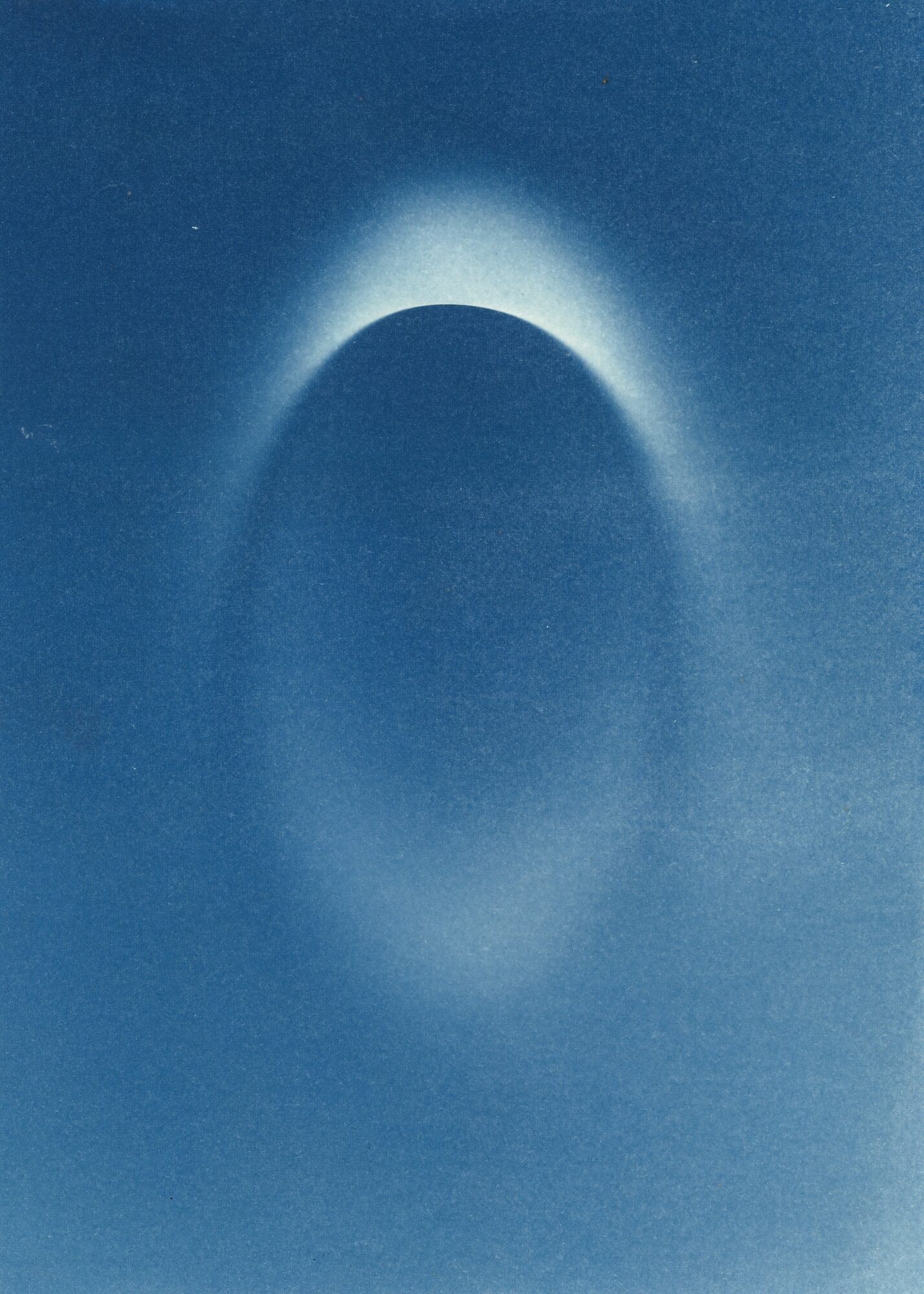 Dark circular shape with a bright halo around the top edge, set against a blue background.