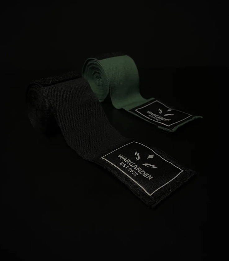 Two fabric tags, one black and one green, with white text and symbols, on a dark background.