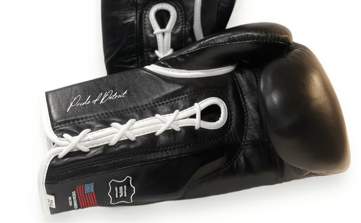 Black boxing glove with white laces and a signature, isolated on white background.