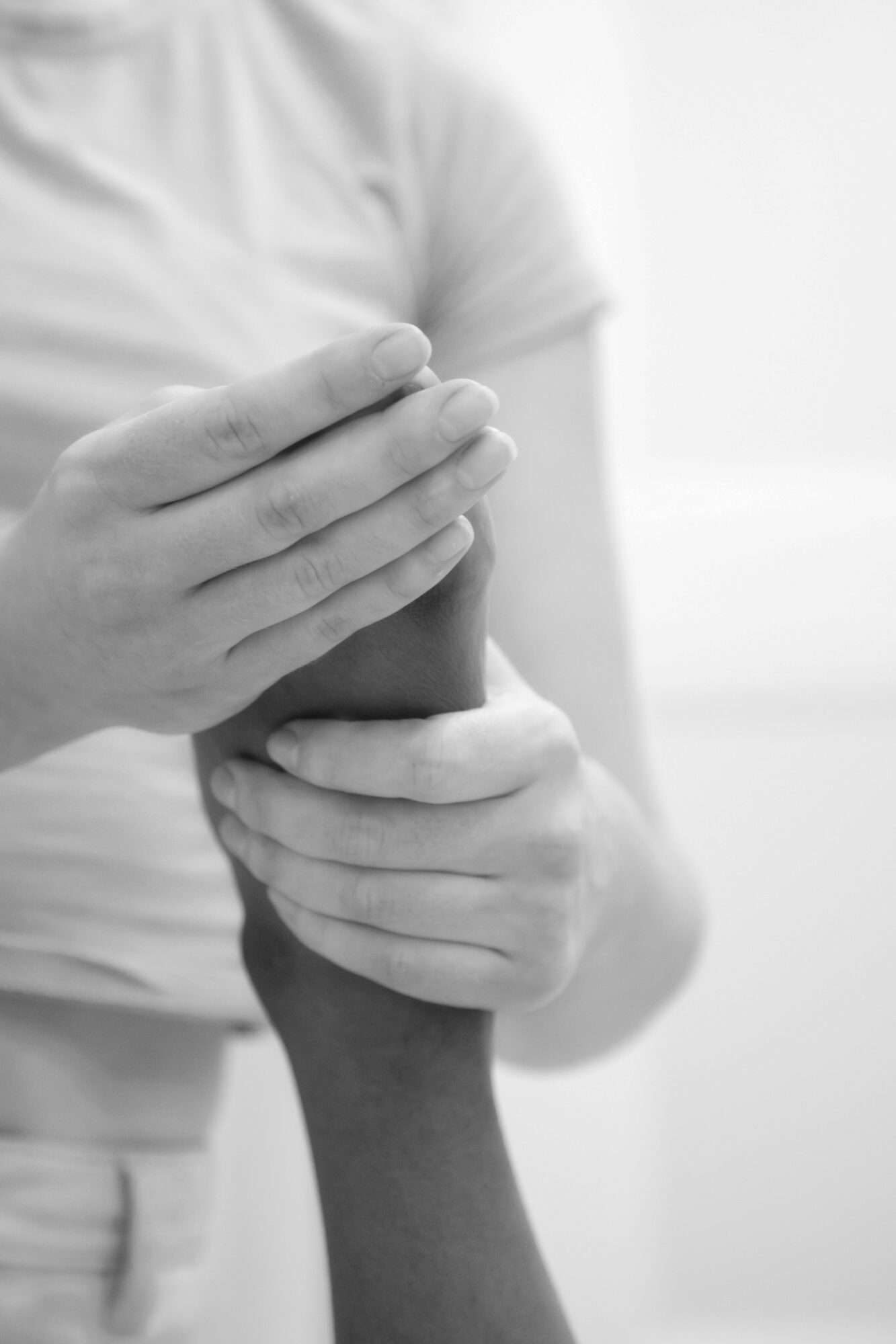 Person holding another person's wrist with both hands, in black and white.
