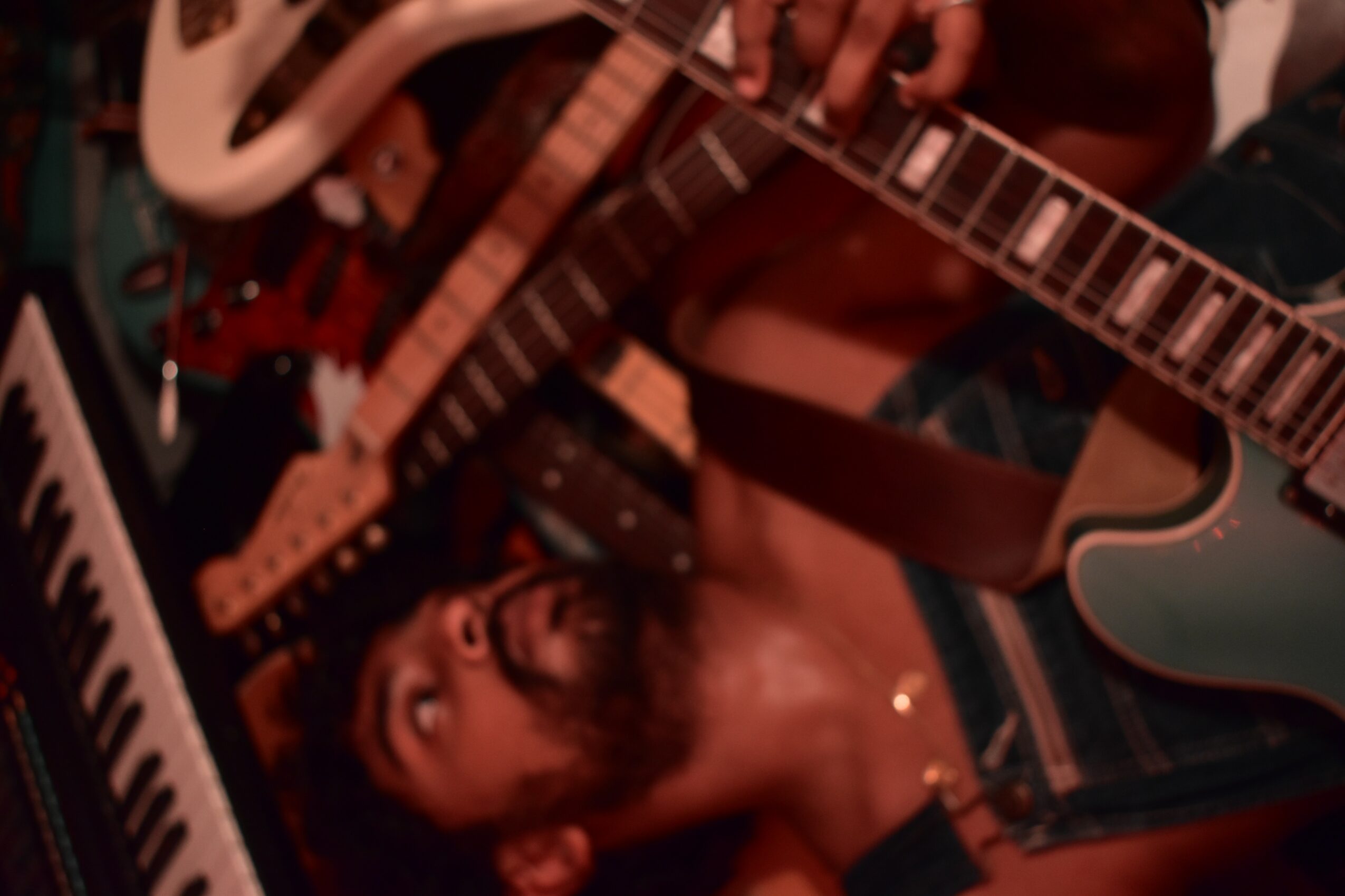 Multiple guitars and a person playing guitar, with a focus on the person's face and hands.