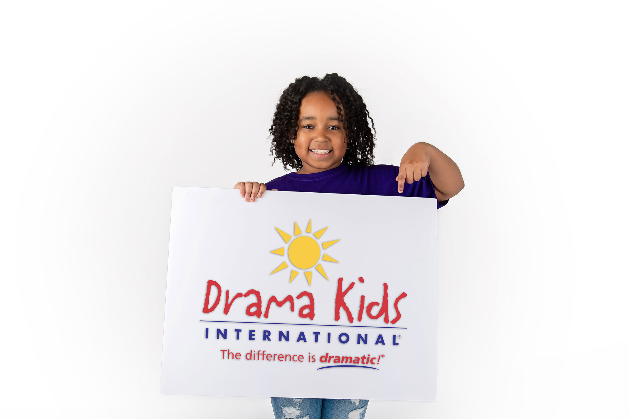Child holding a sign with a sun logo and text, smiling, against a white background.