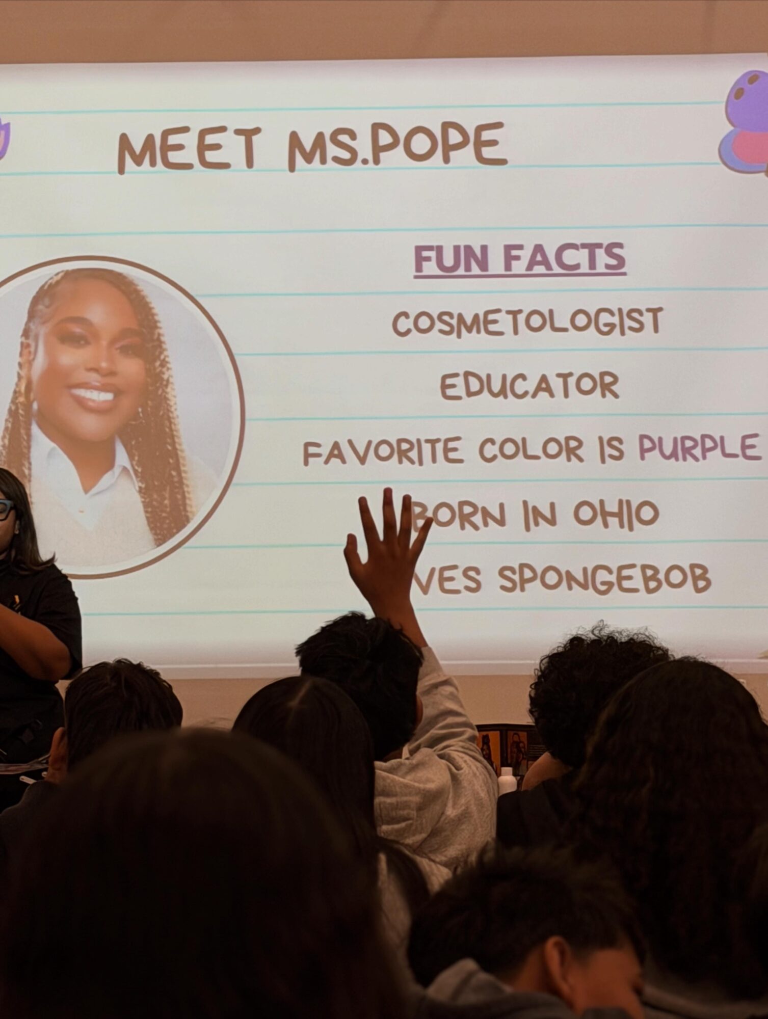 Classroom presentation slide introduces Ms. Pope with fun facts, including her profession, favorite color, and birthplace, with students raising hands.