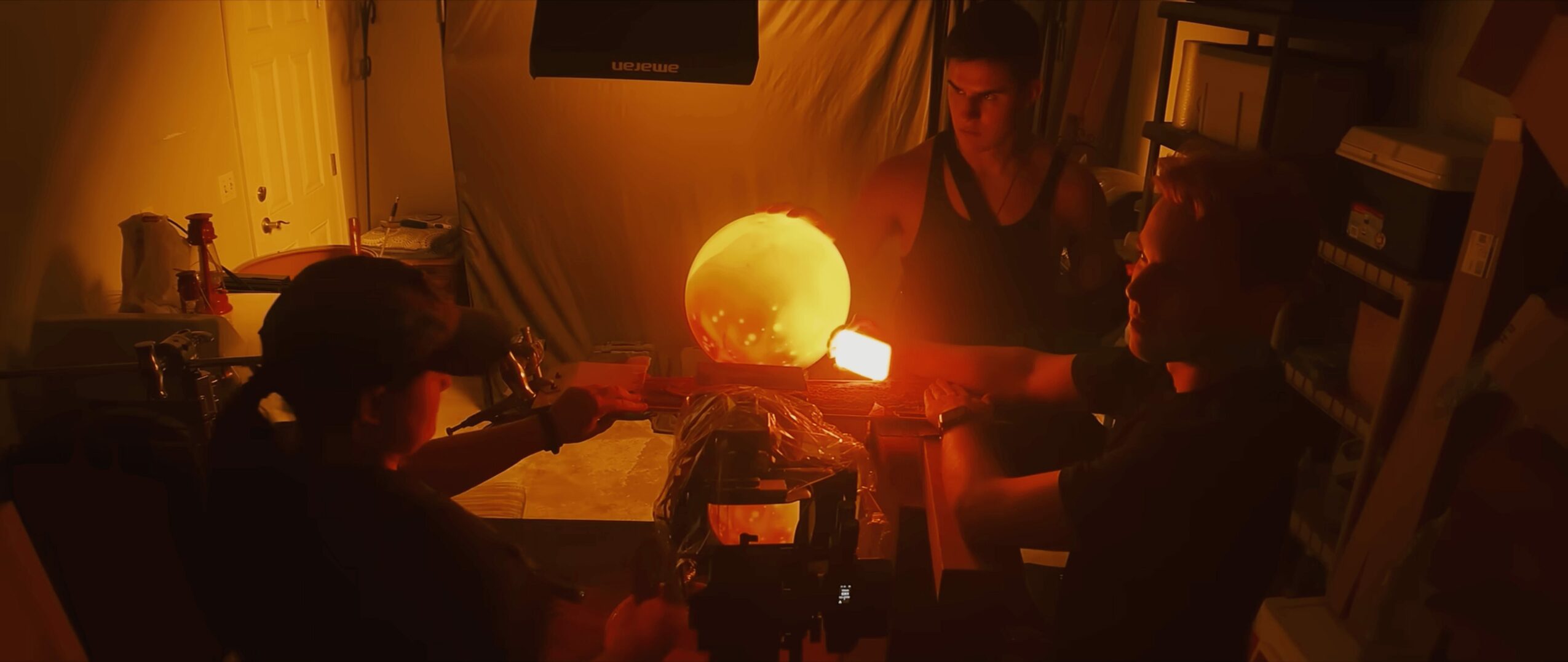 Group of people gathered around a glowing spherical object in a dimly lit room.