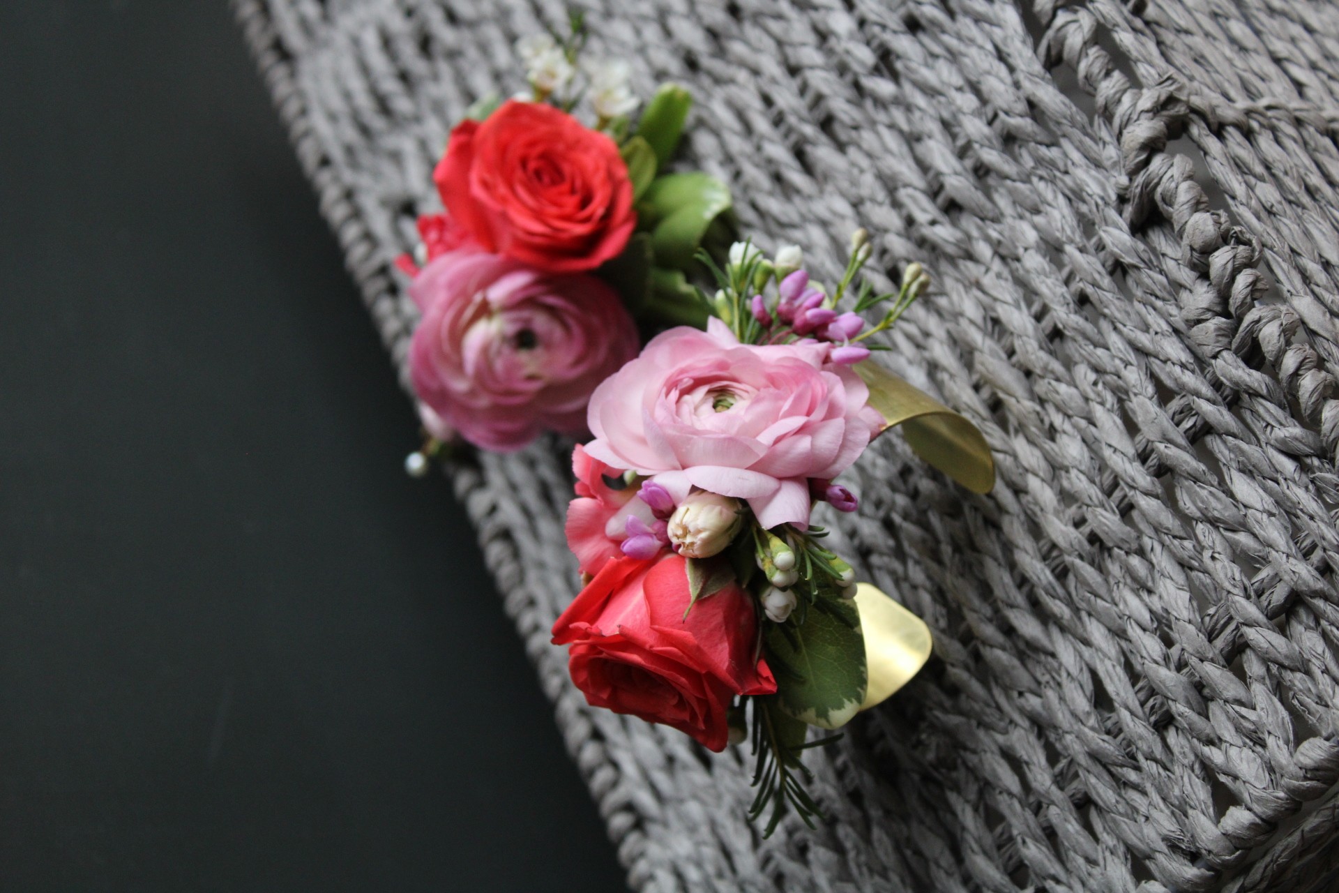 Pink and red roses with green leaves on a textured gray surface.