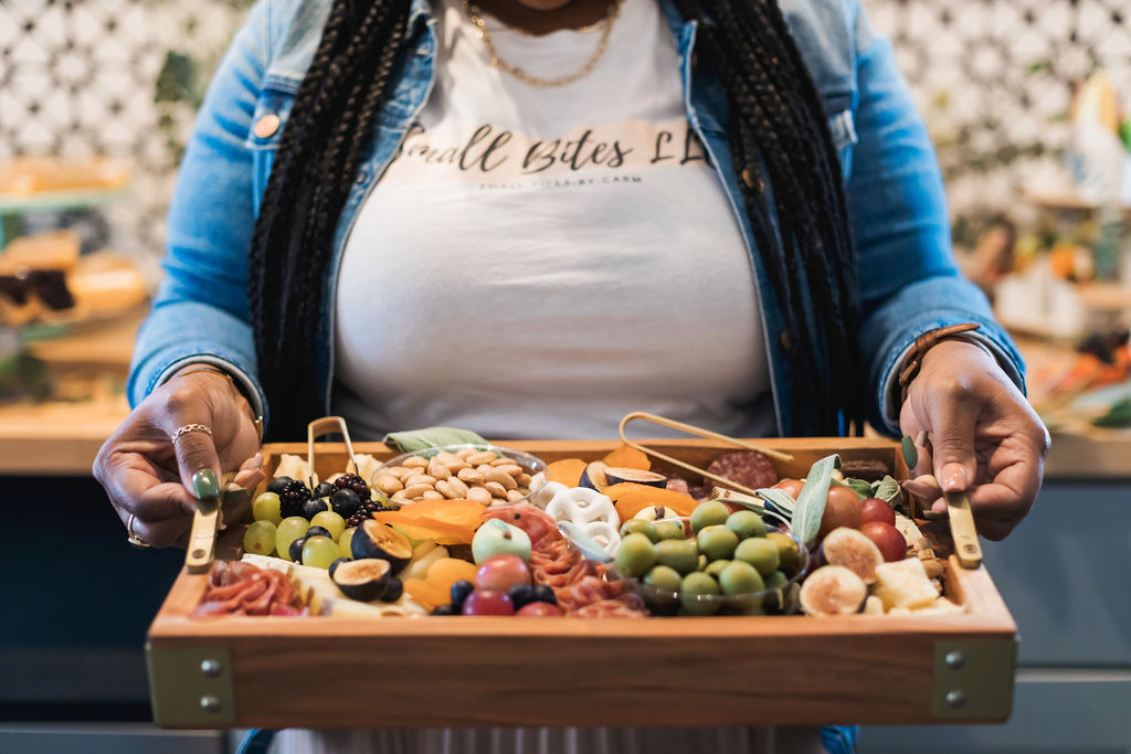 Person holding a tray of assorted colorful candies and chocolates in a store, with blurred background.