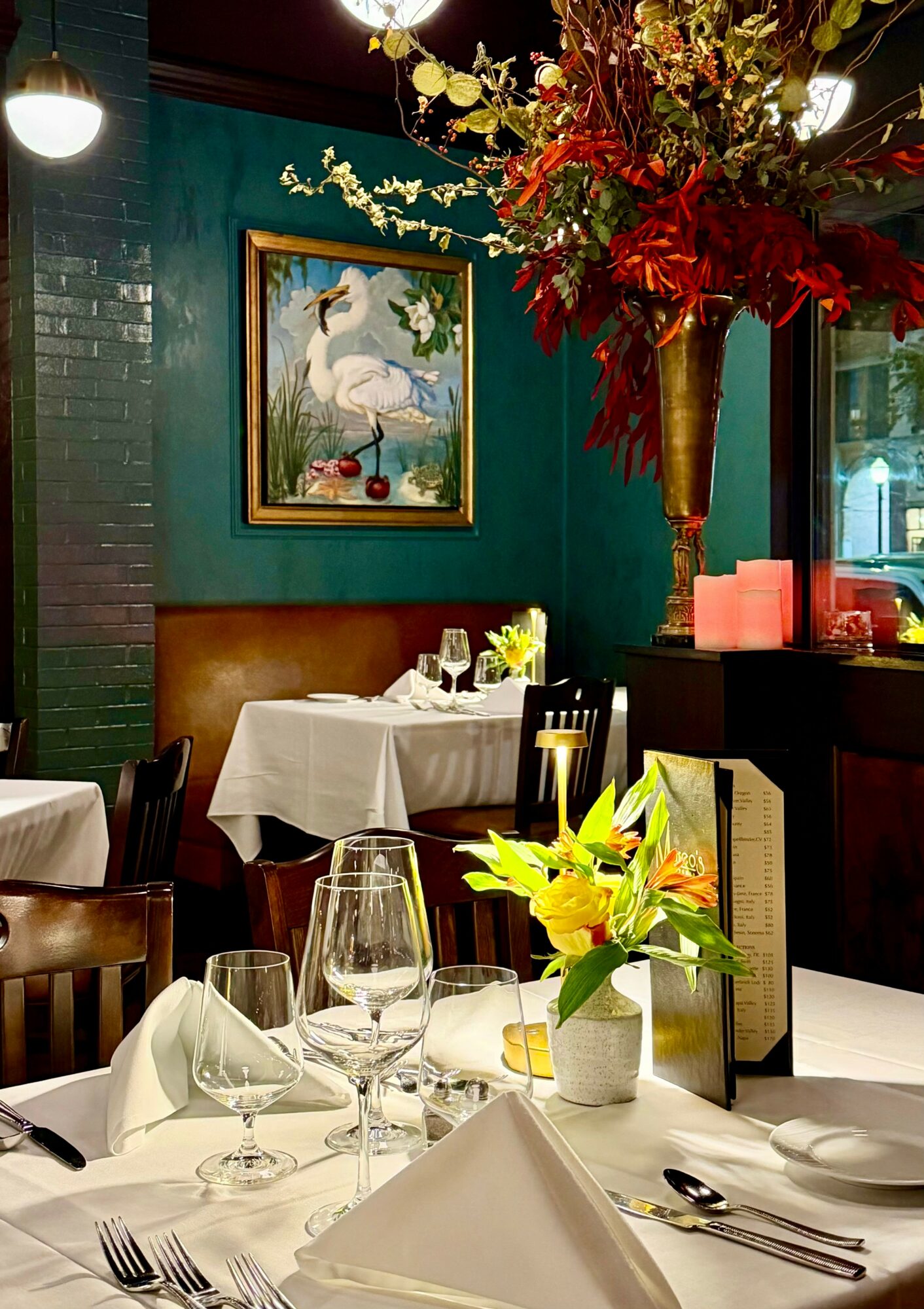 Elegant restaurant interior with a table set for dining, a floral arrangement, and artwork on the wall.
