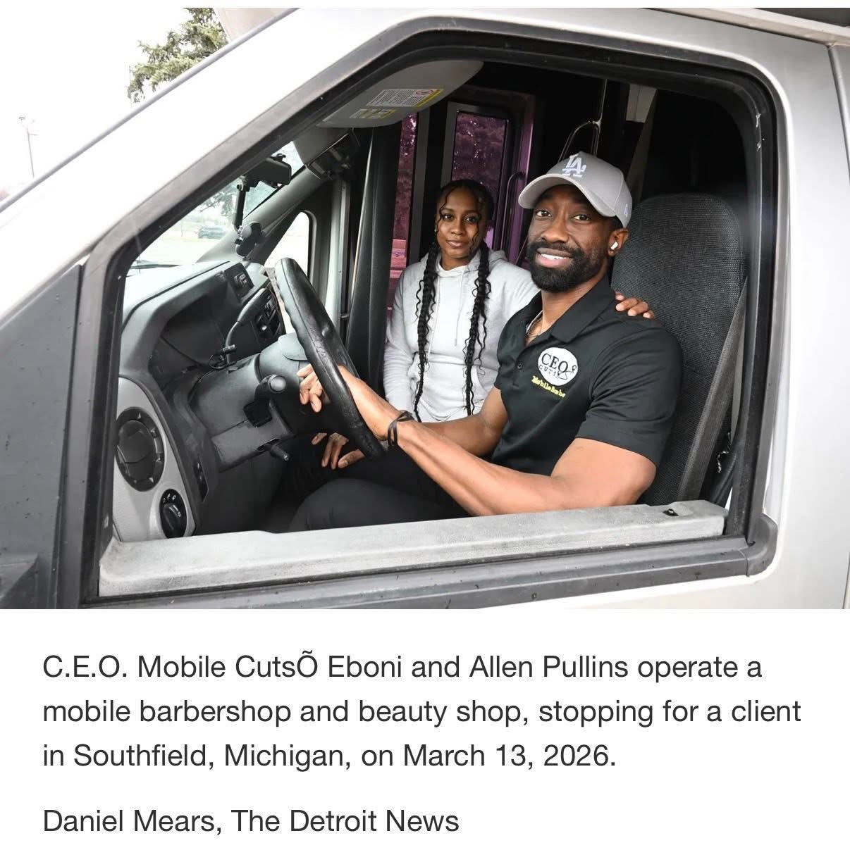 Man and girl sitting in a vehicle, smiling, with the man in the driver's seat and the girl standing beside him, inside a vehicle.