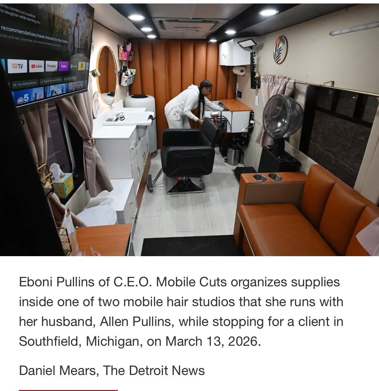 Interior of a mobile hair studio with a person working at a station, sofa, and various salon equipment visible.