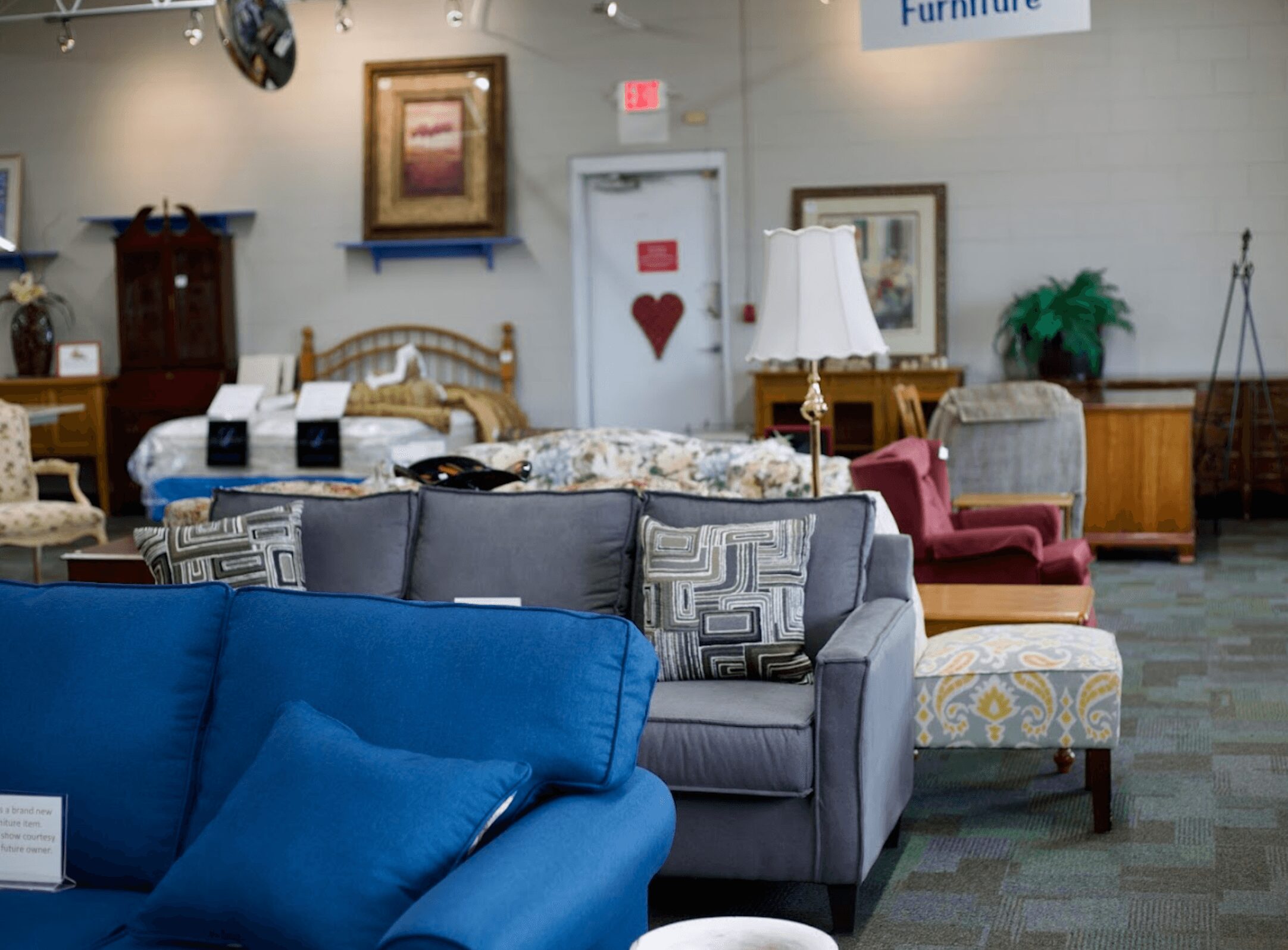 Furniture store interior with sofas, chairs, lamps, and artwork on walls.
