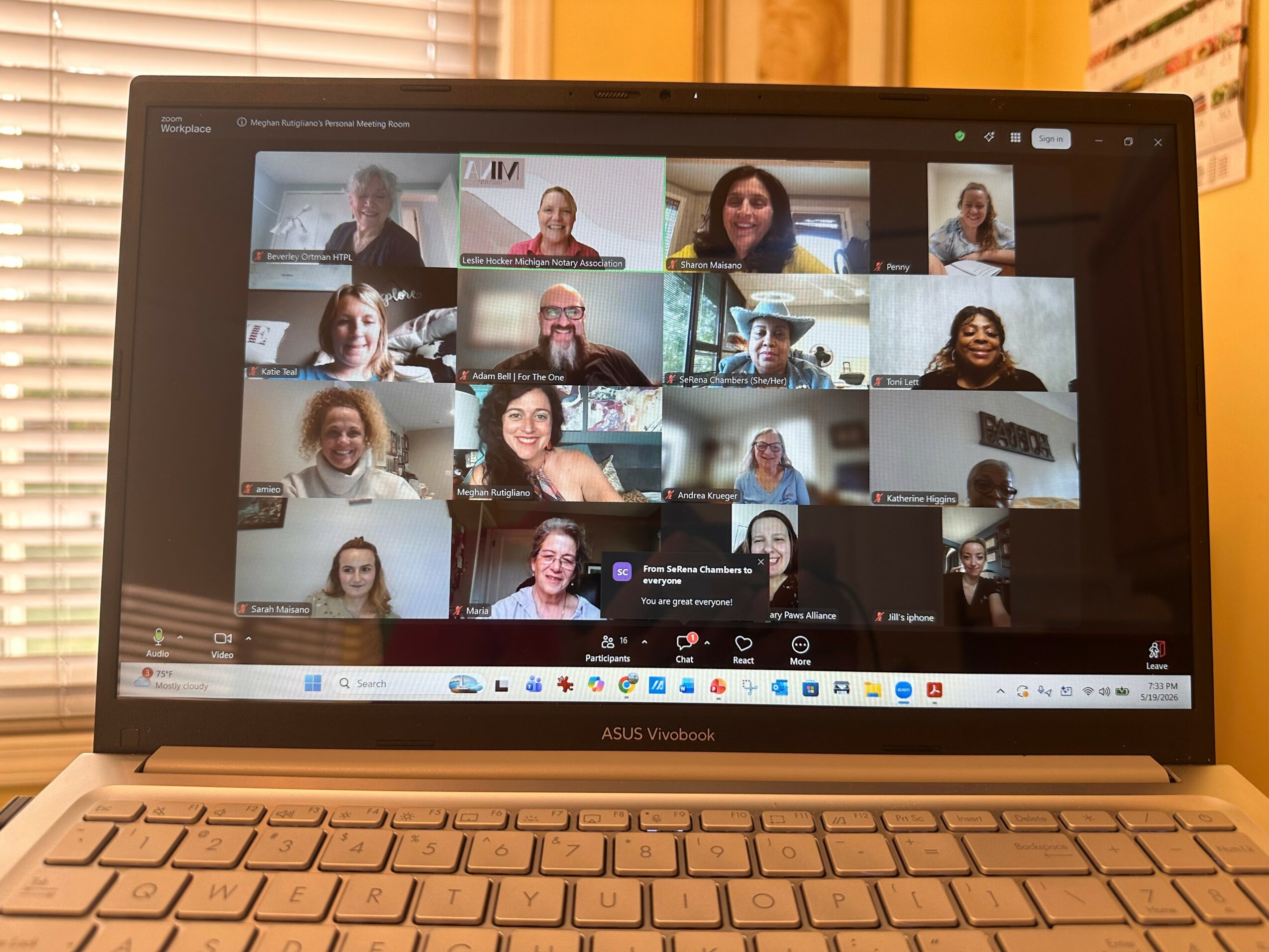 Laptop screen displaying a video conference with multiple participants in grid view.