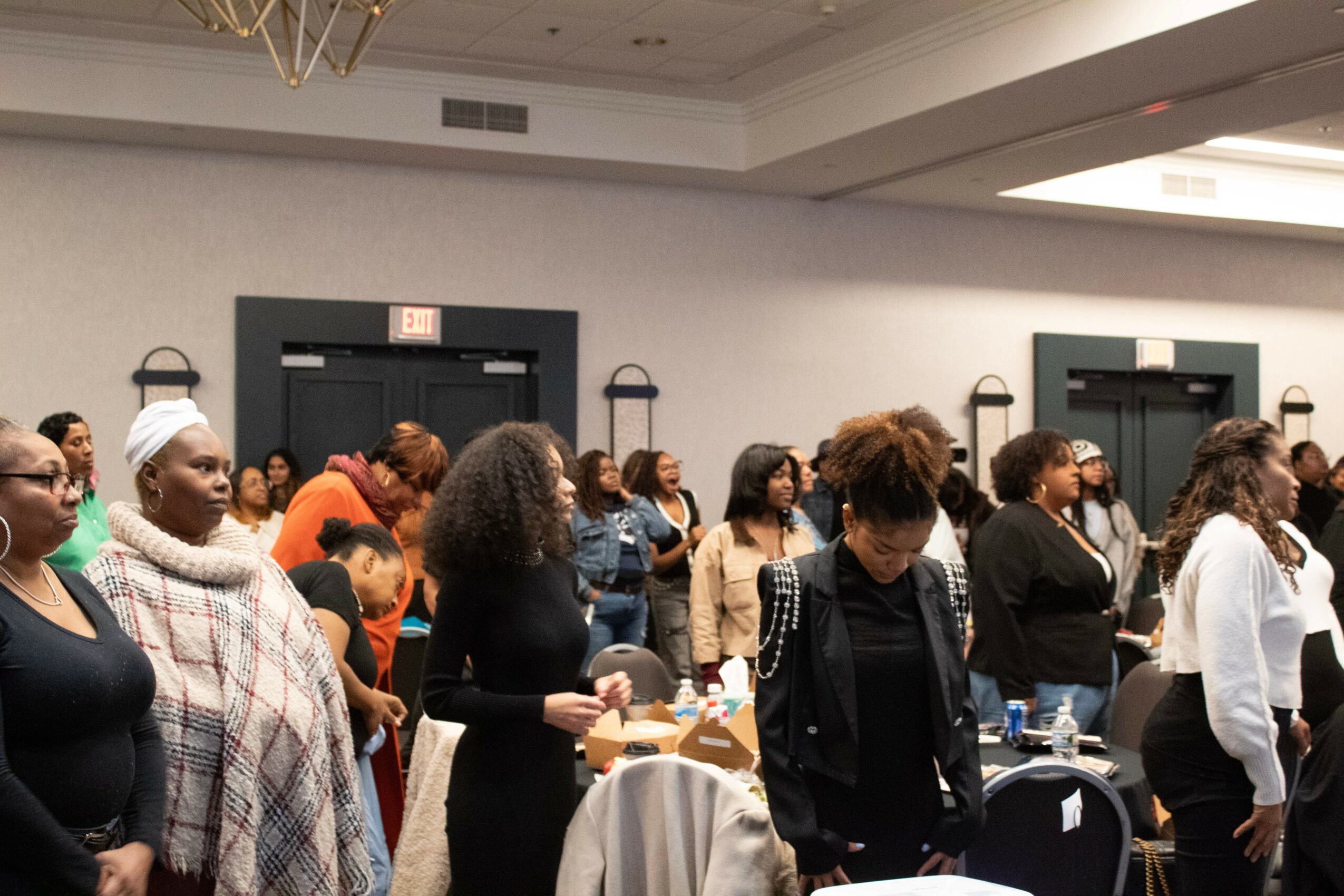 Group of people gathered in a conference room, some standing near tables, engaging in conversation and activities.
