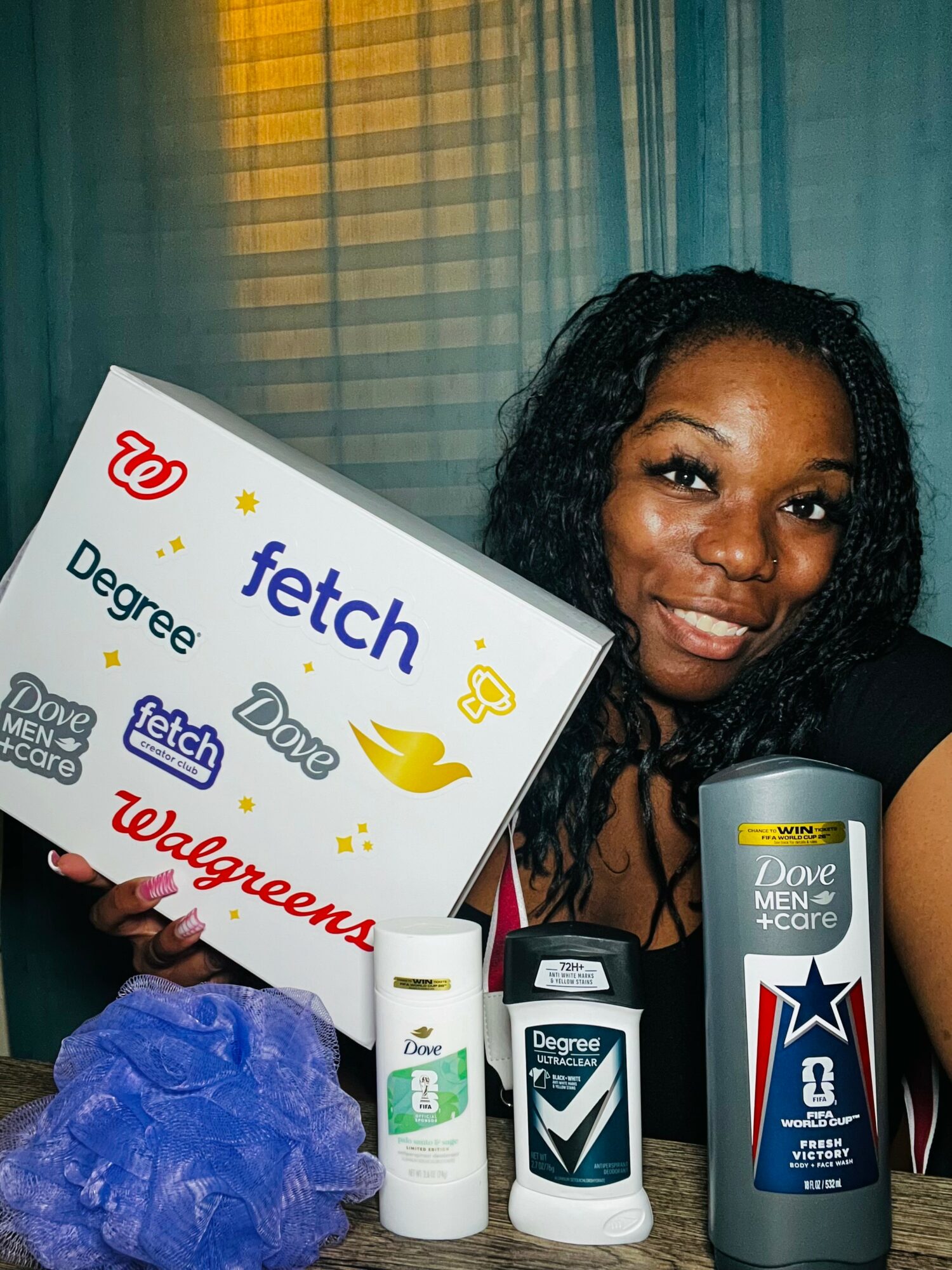 Smiling woman holding a Walgreens sign with various brand logos, standing in front of a window with curtains.