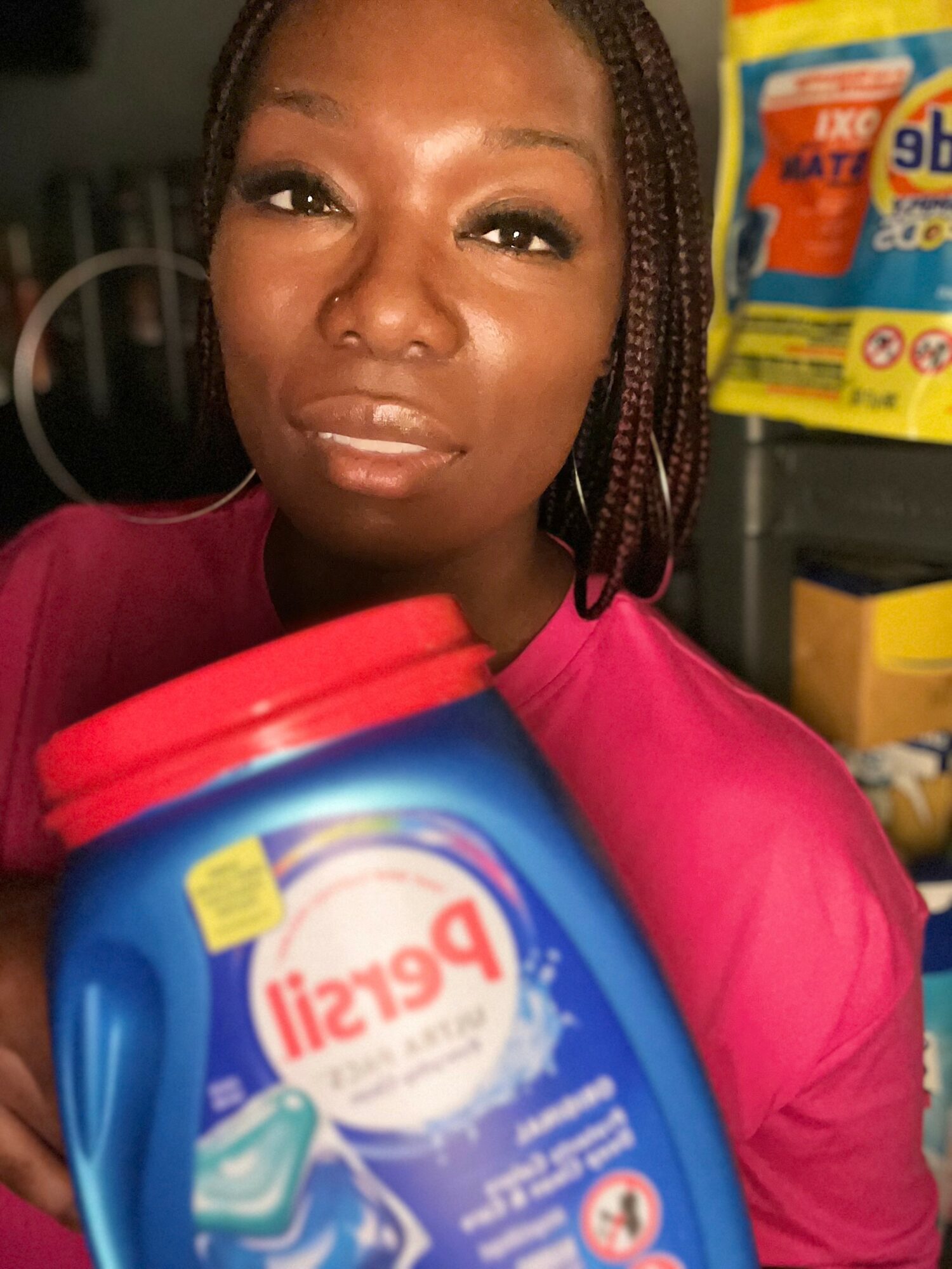 Woman with braided hair holding a blue container of Persil detergent in a store aisle.