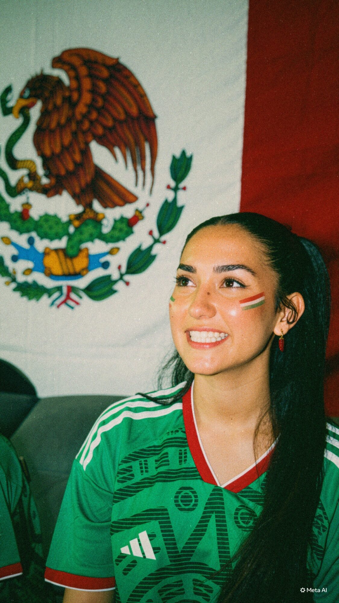 Young woman with face paint, smiling, wearing a green sports jersey, in front of a Mexican flag with an eagle emblem.