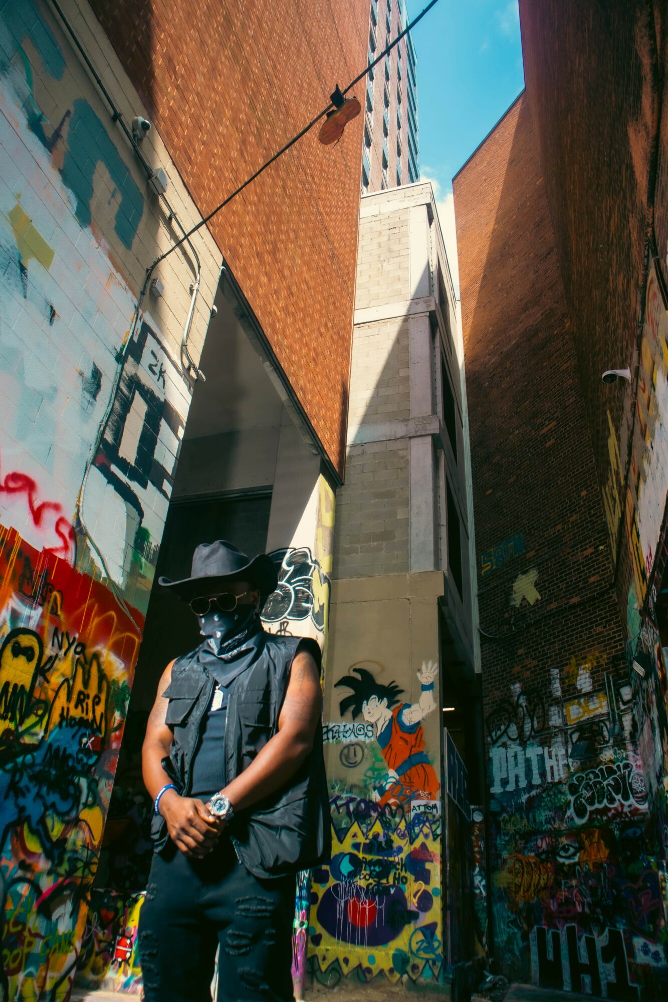 Person wearing a hat and backpack standing in a narrow alley with colorful graffiti walls.