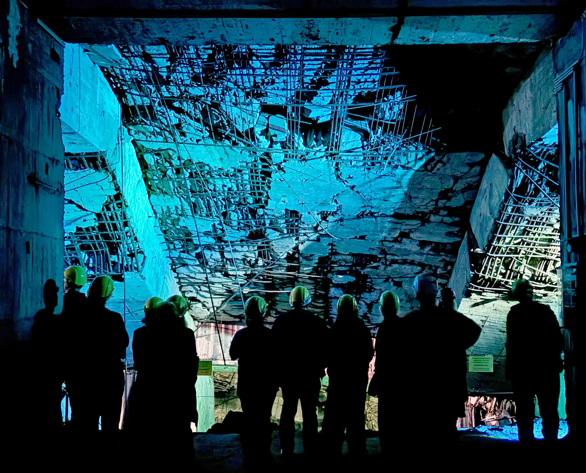 Group of people looking at a large, illuminated, abstract digital display or artwork in a dark space.