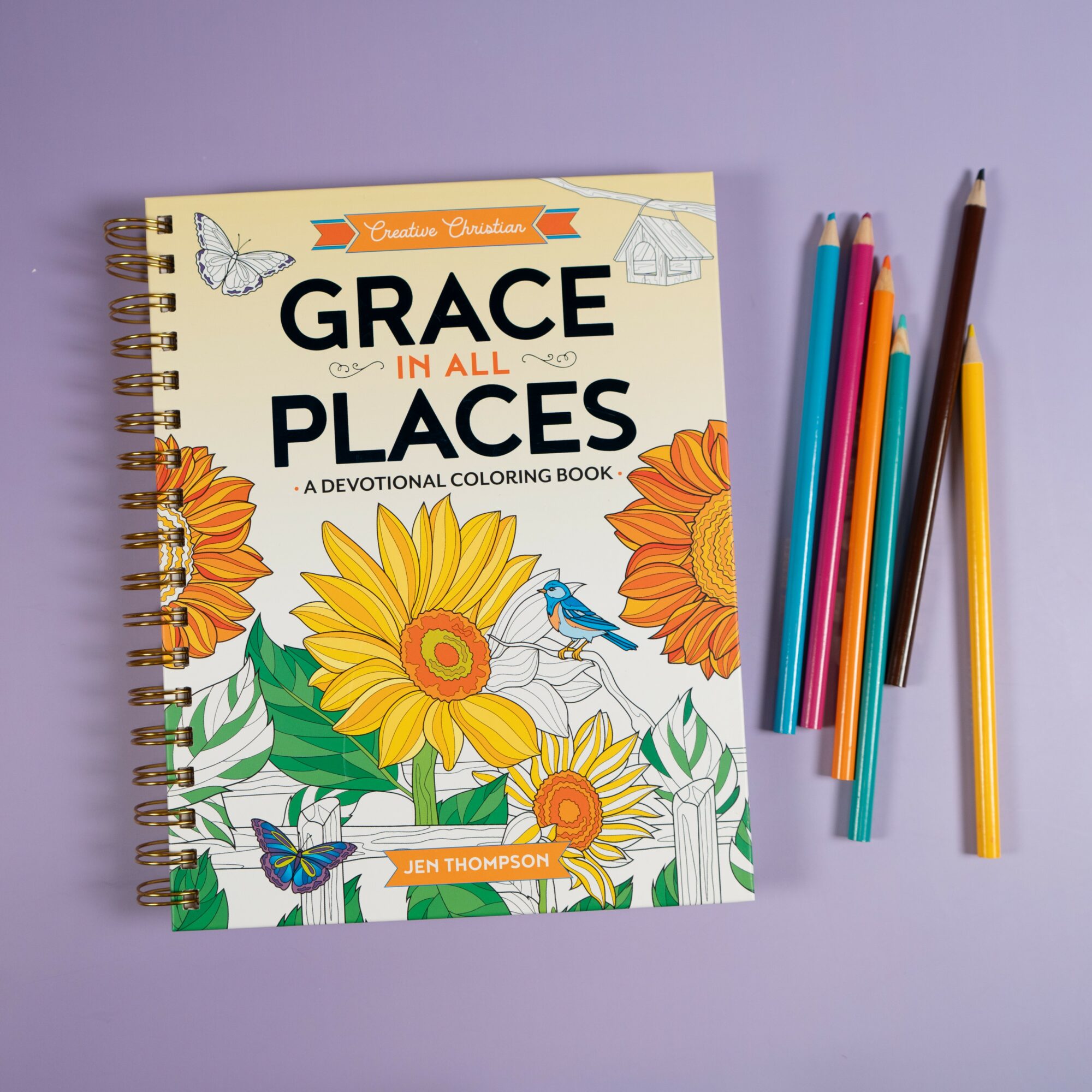 Coloring book titled 'Grace in All Places' with colorful pens on a purple background.