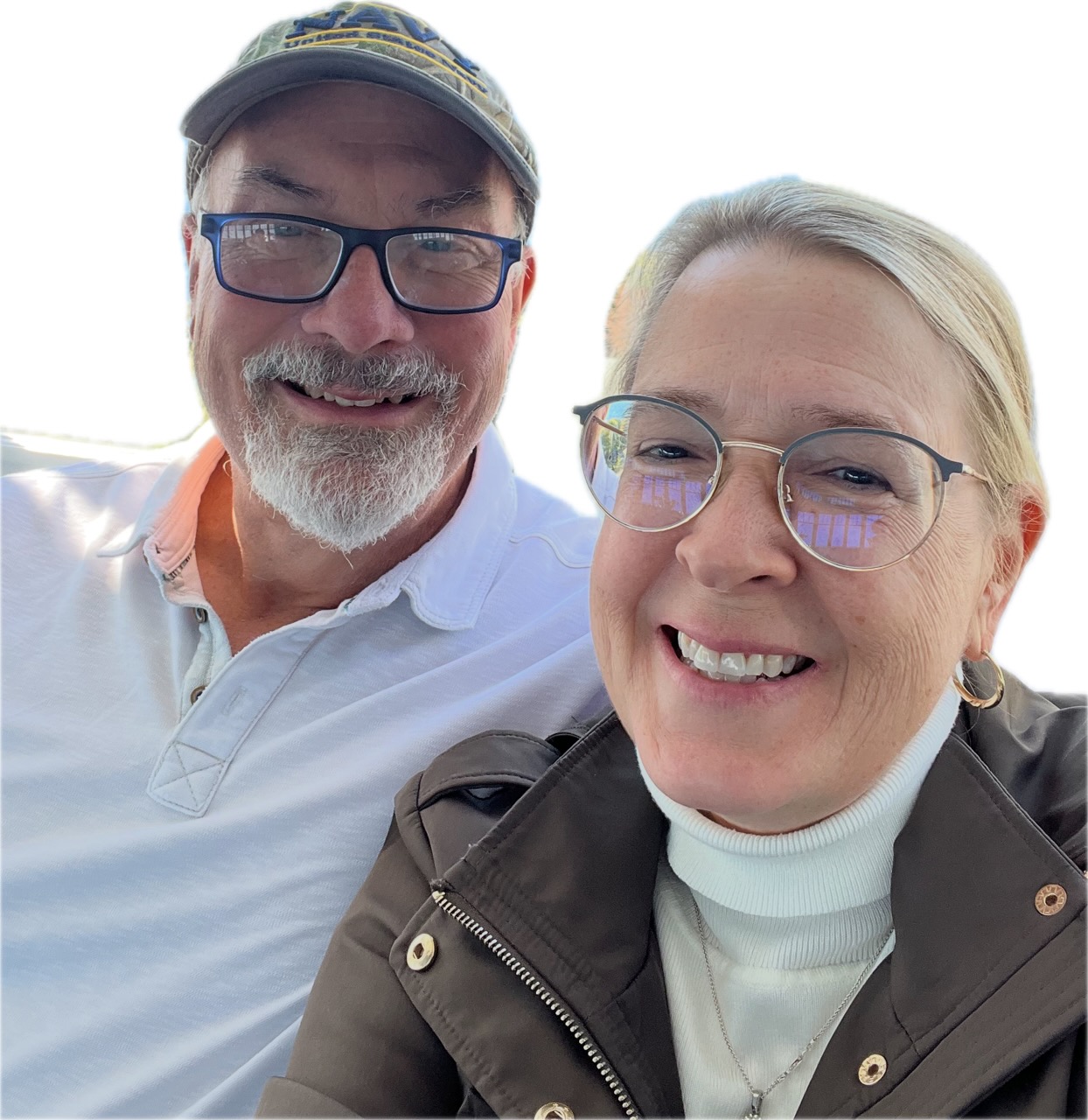Two smiling people, a man with glasses and a woman with glasses, close together outdoors, both wearing casual clothing.