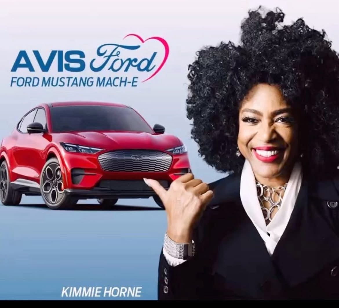 Woman with curly hair smiling and pointing at a red Ford Mustang Mach-E, with AVIS Ford logo and text, background light blue.