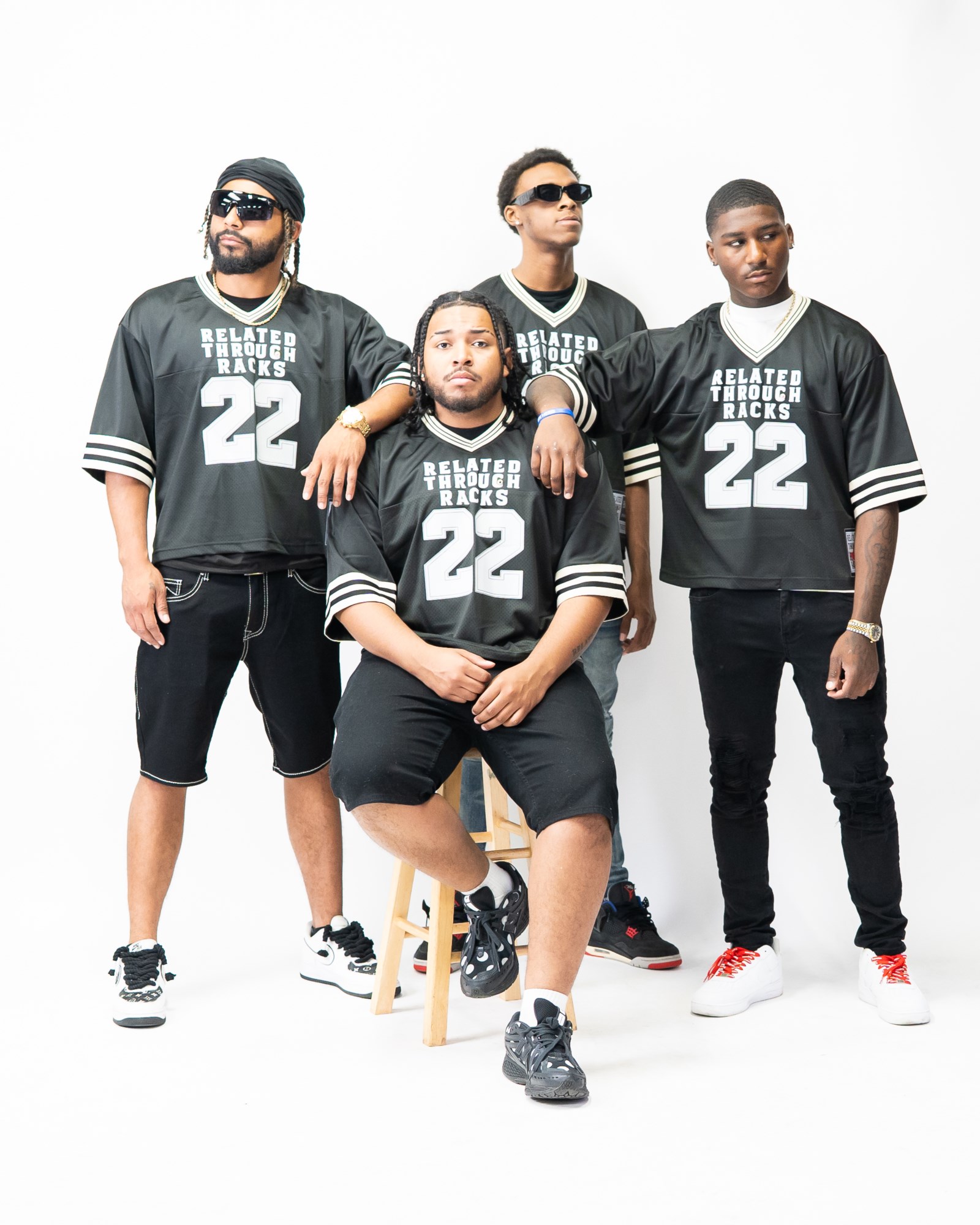 Four young men in black sports jerseys with white numbers and text, posing together against a white background.