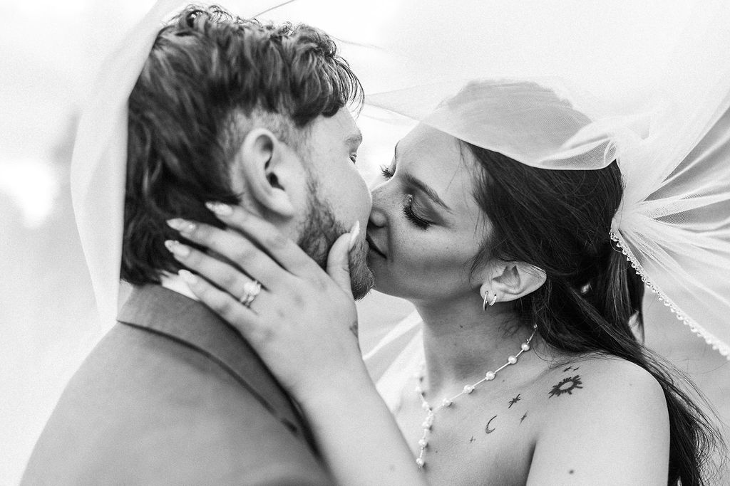 A couple is about to kiss, with the woman holding the man's face gently, both with eyes closed.