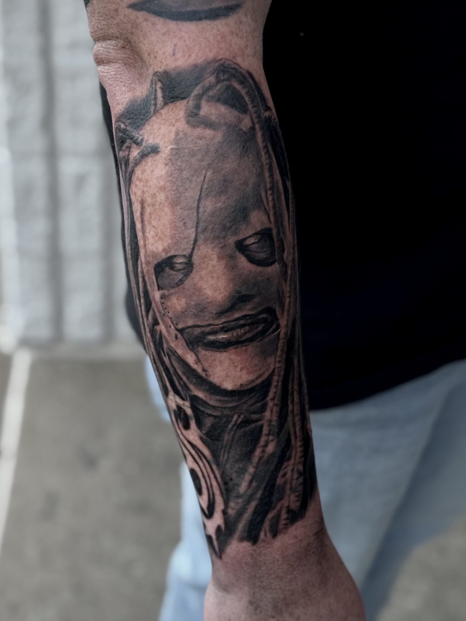 Tattoo of a smiling woman's face on a person's arm, with long hair and detailed features.