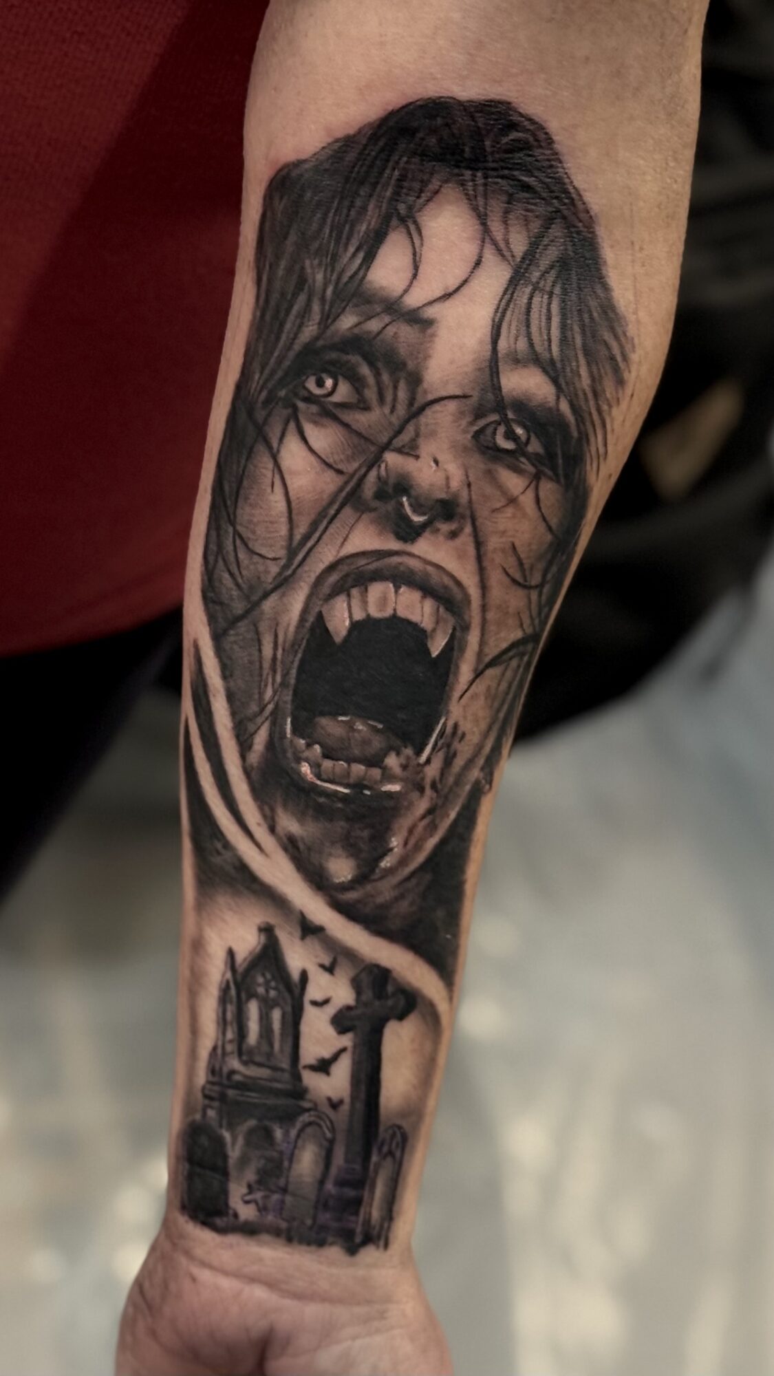 Tattoo of a screaming woman's face with open mouth and dark hair, and a church with a cross below.