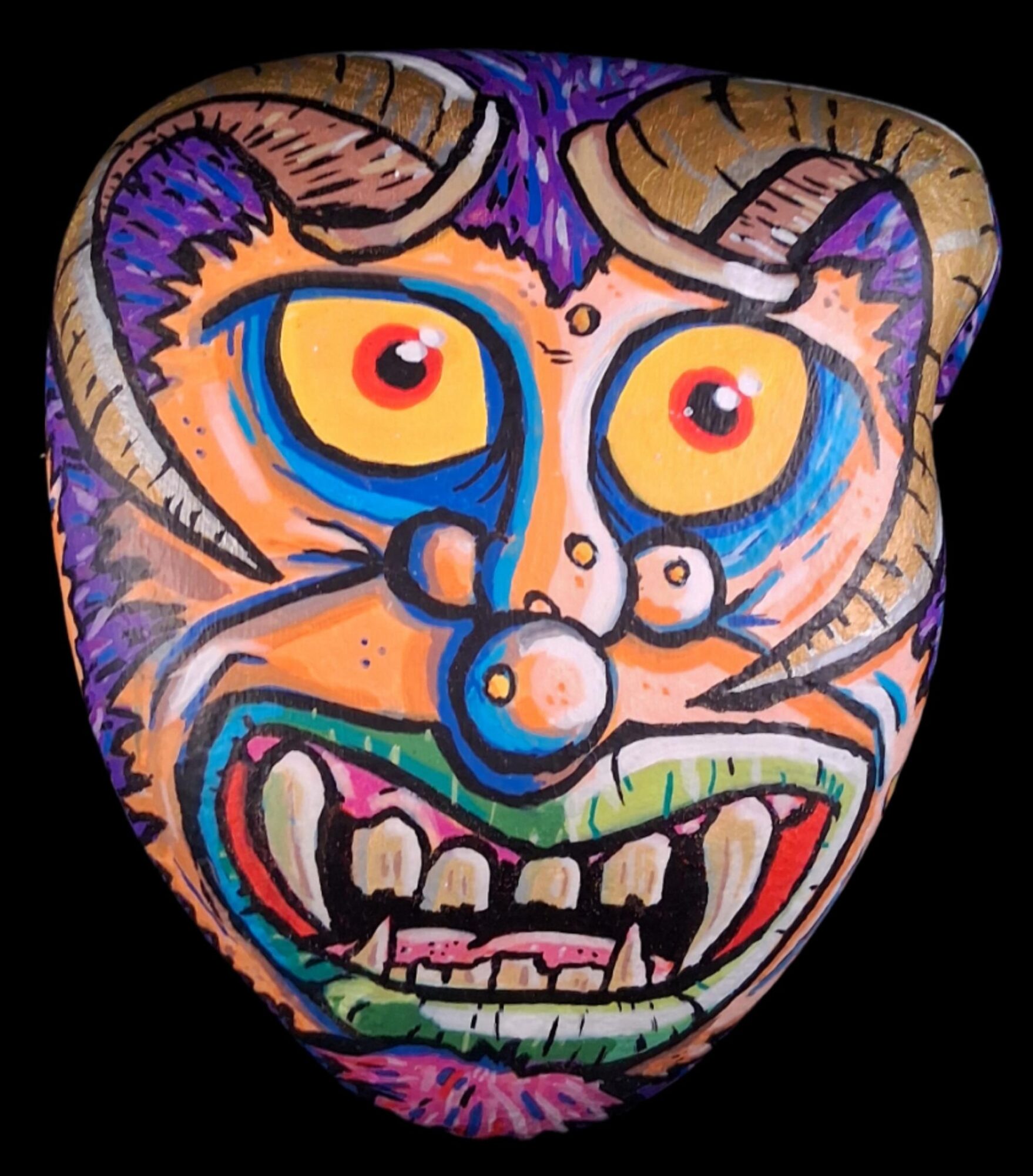 Colorful, abstract face with horns, large eyes, and a wide, toothy grin on a black background.
