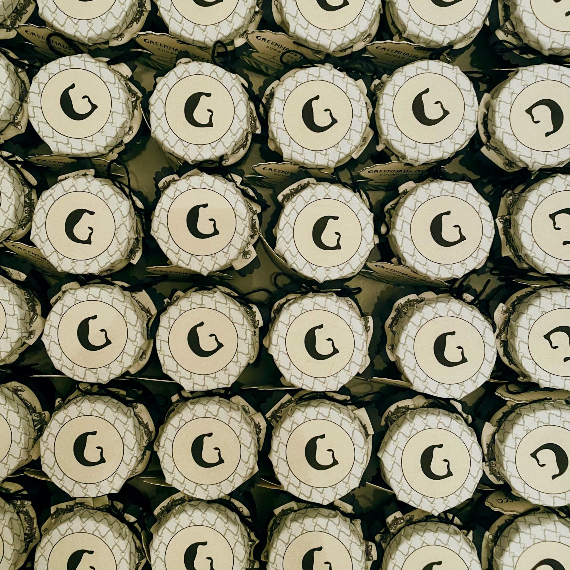 Stacked cylindrical objects with a logo featuring a stylized letter G, arranged in a grid pattern.