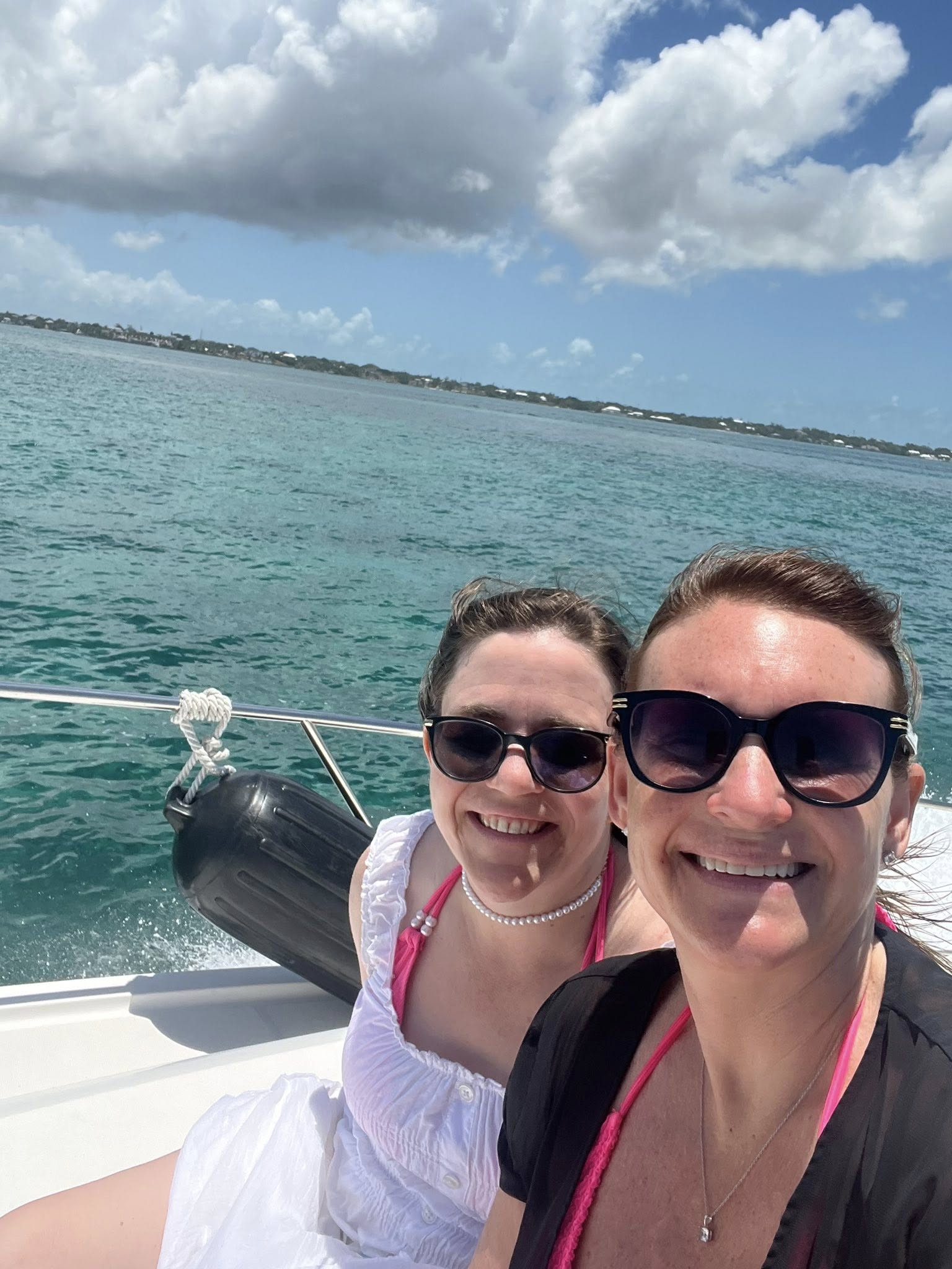Two people smiling on a boat with water and sky in the background.