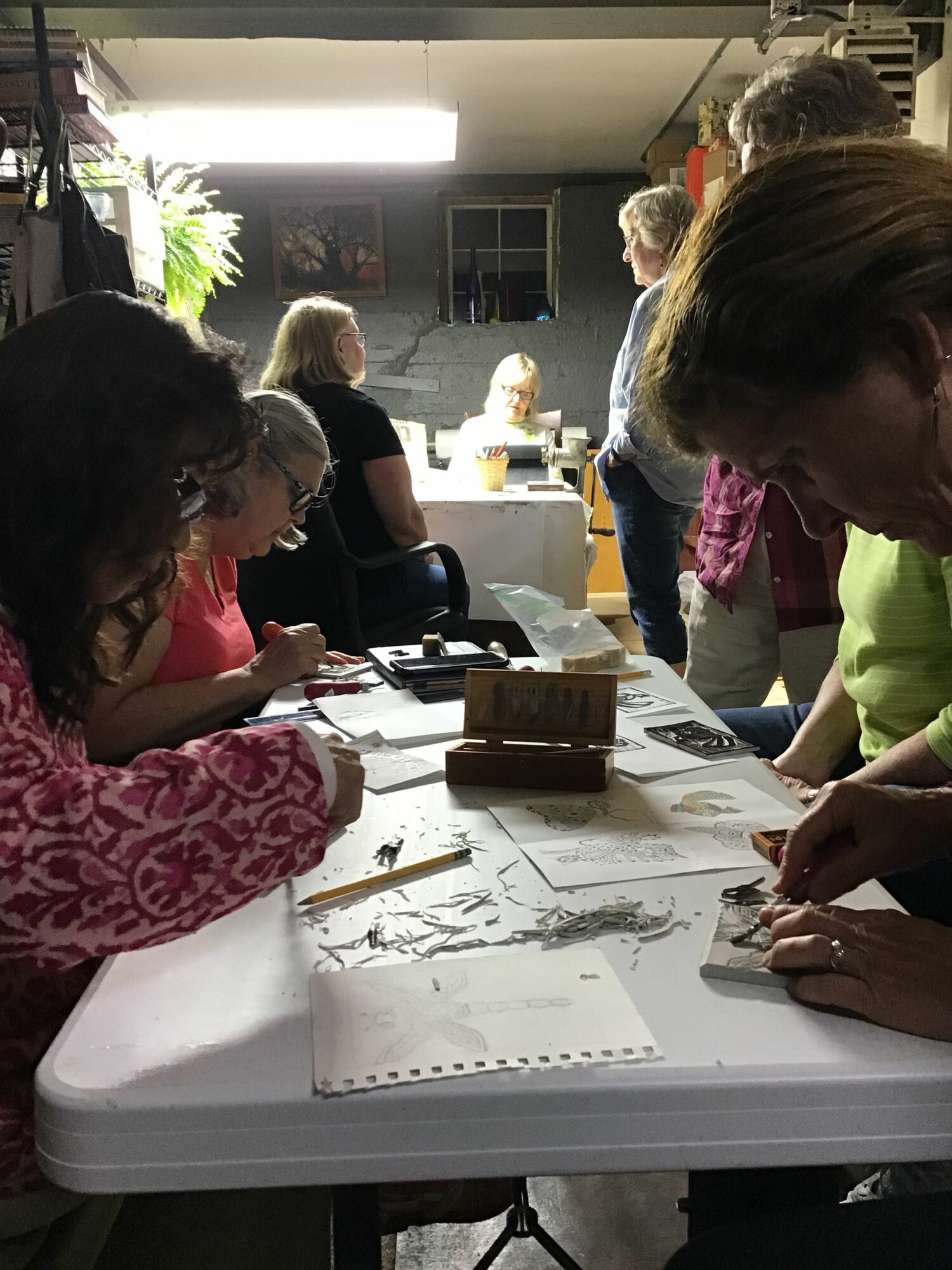 People gathered around a table working on a project with papers and tools in a room with bright lighting.