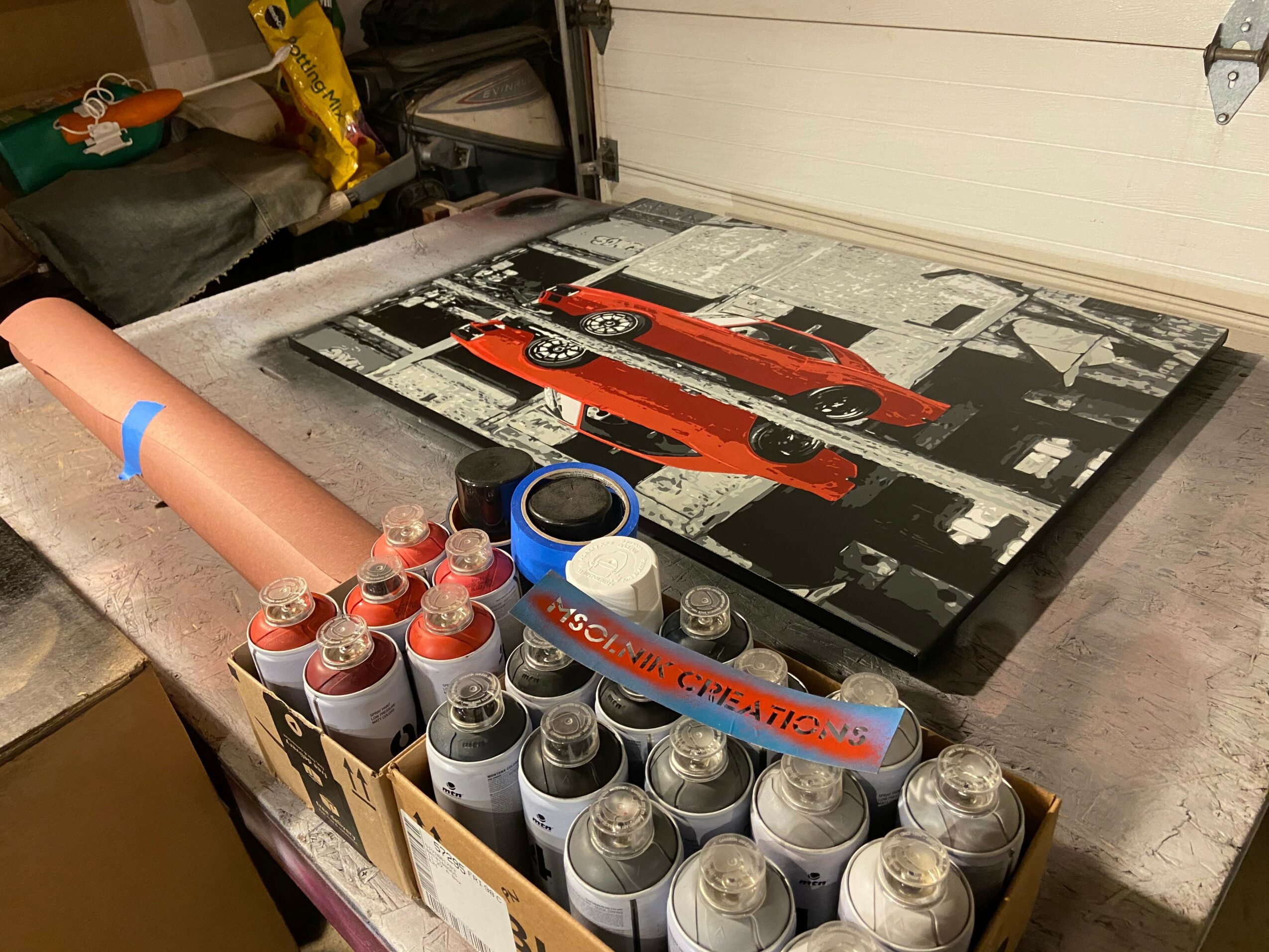 A painting of a red vintage car on a black and white city street scene, with spray paint cans and a cardboard tube in the foreground.