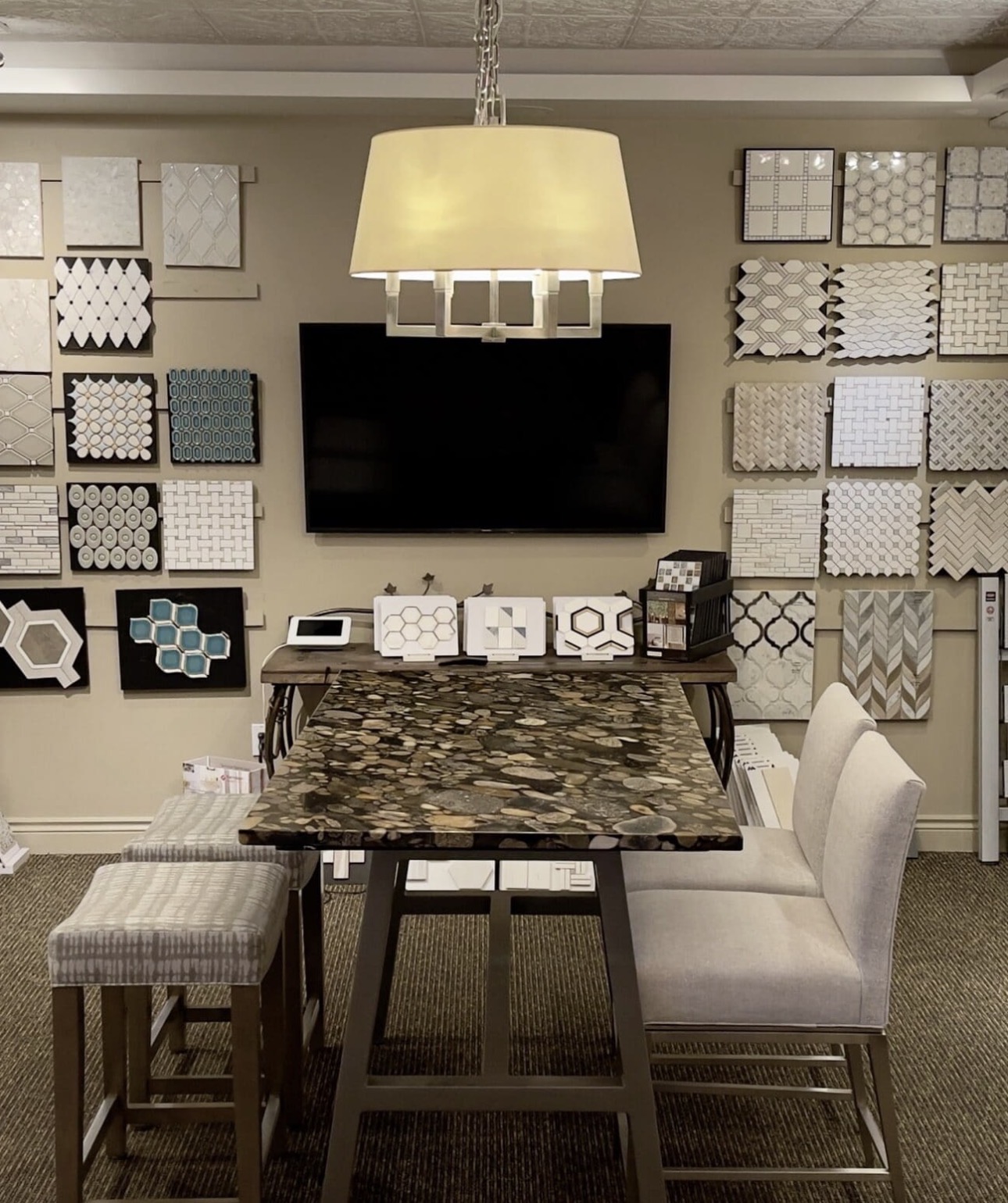 Dining room with a table, chairs, wall art, a TV, and a hanging light fixture, with a beige wall and carpeted floor.