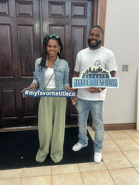 Two people standing indoors, holding a sign with a city skyline and the hashtag #mylavoraconfuerteco, smiling at the camera.