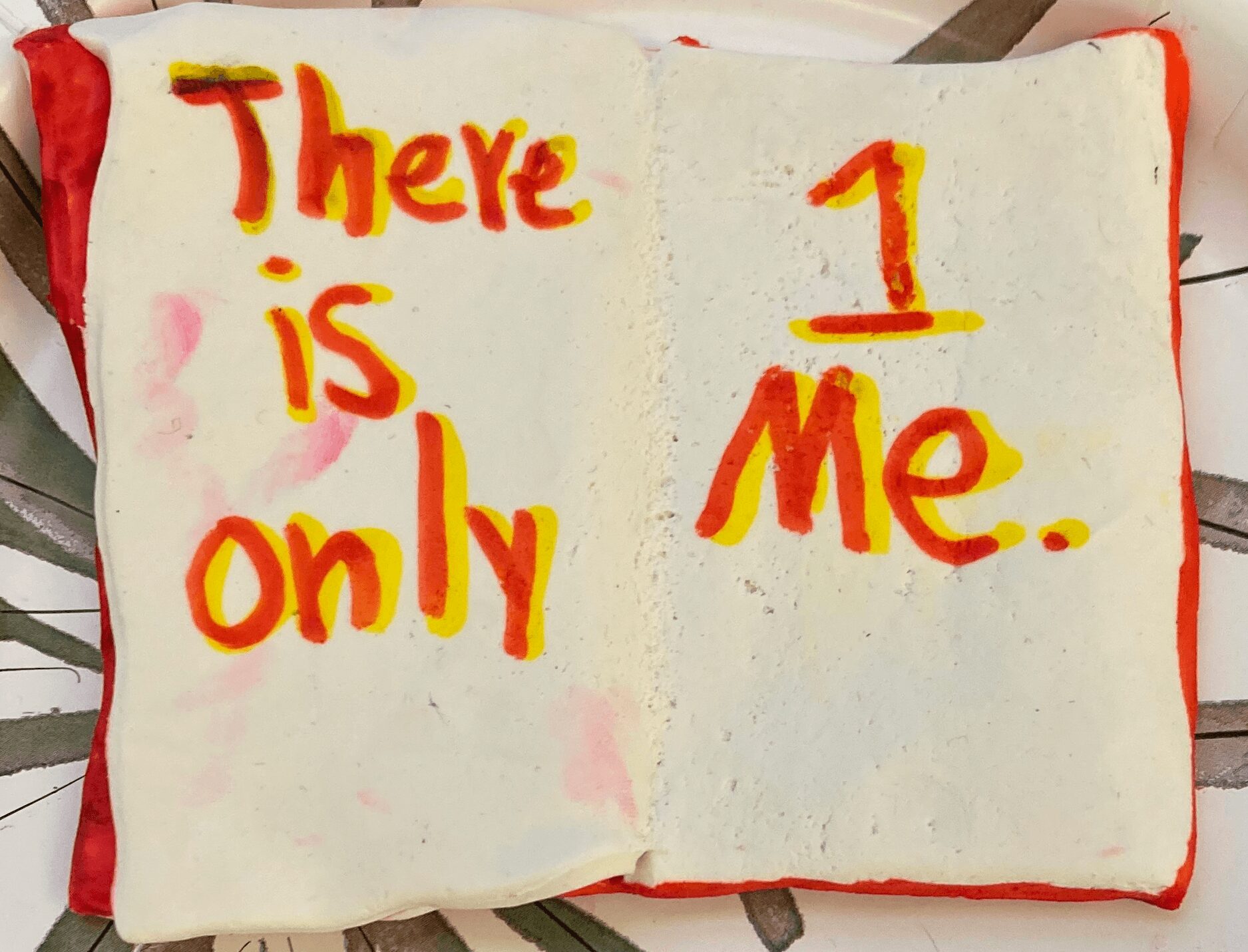 Open book with handwritten message: 'There is only 1 Me.' in red and yellow on white pages.