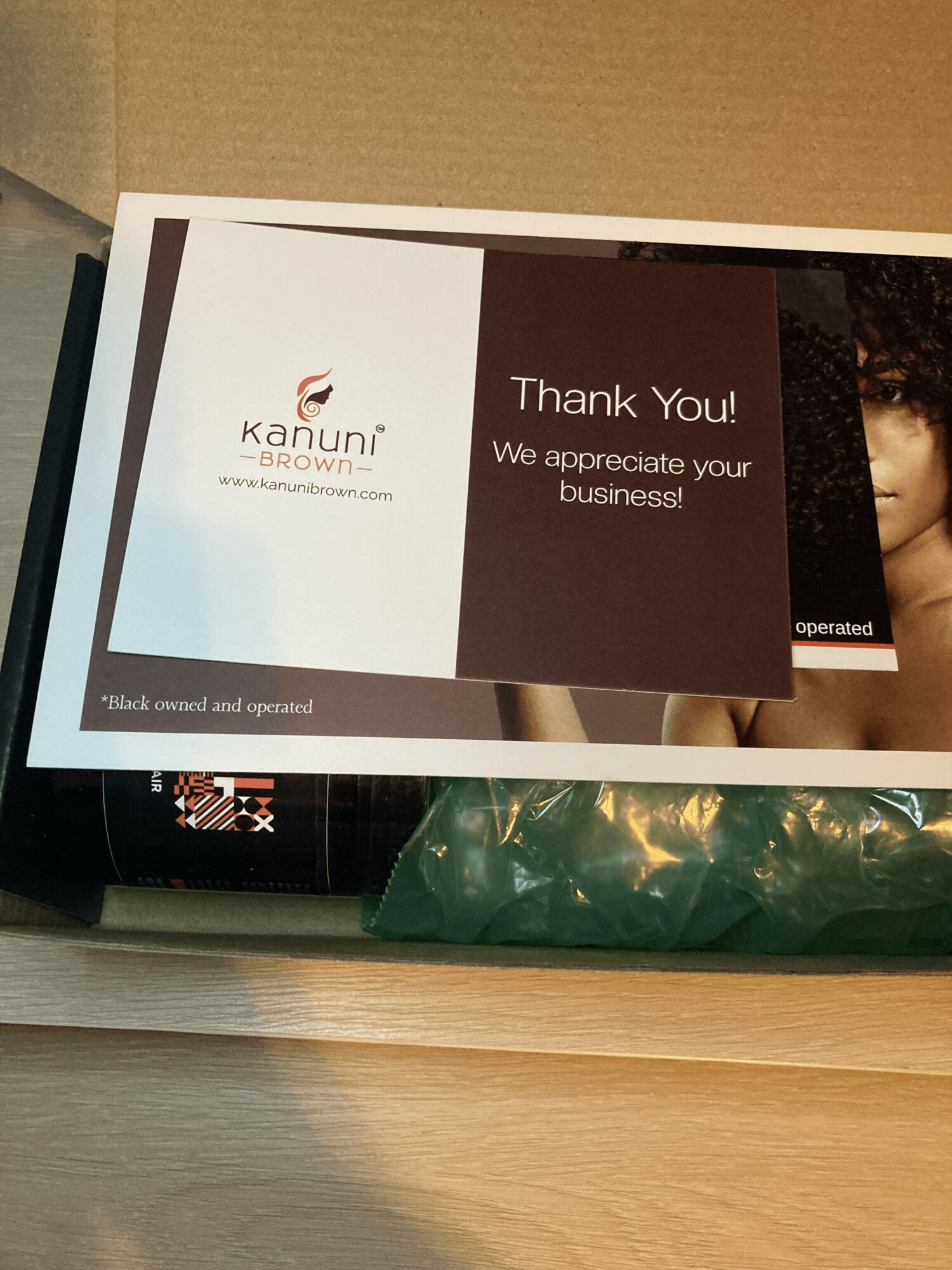 Thank you card from Kanuni Browni with a message of appreciation, placed on a surface with some packaging underneath.
