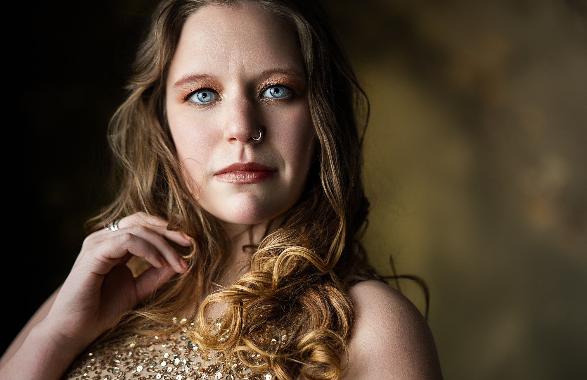 Close-up portrait of a woman with long, wavy hair and blue eyes, looking directly at the camera.