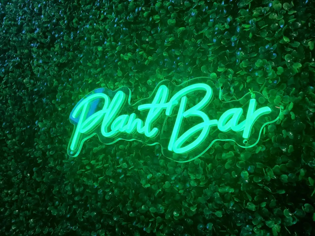 Neon sign reads 'Plant Bar' against a leafy green background.