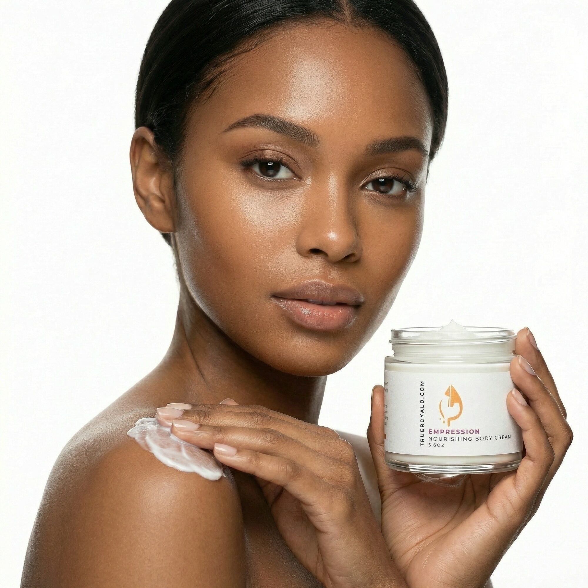 Woman with smooth skin applying cream to her shoulder, holding a jar of skincare product, against a white background.