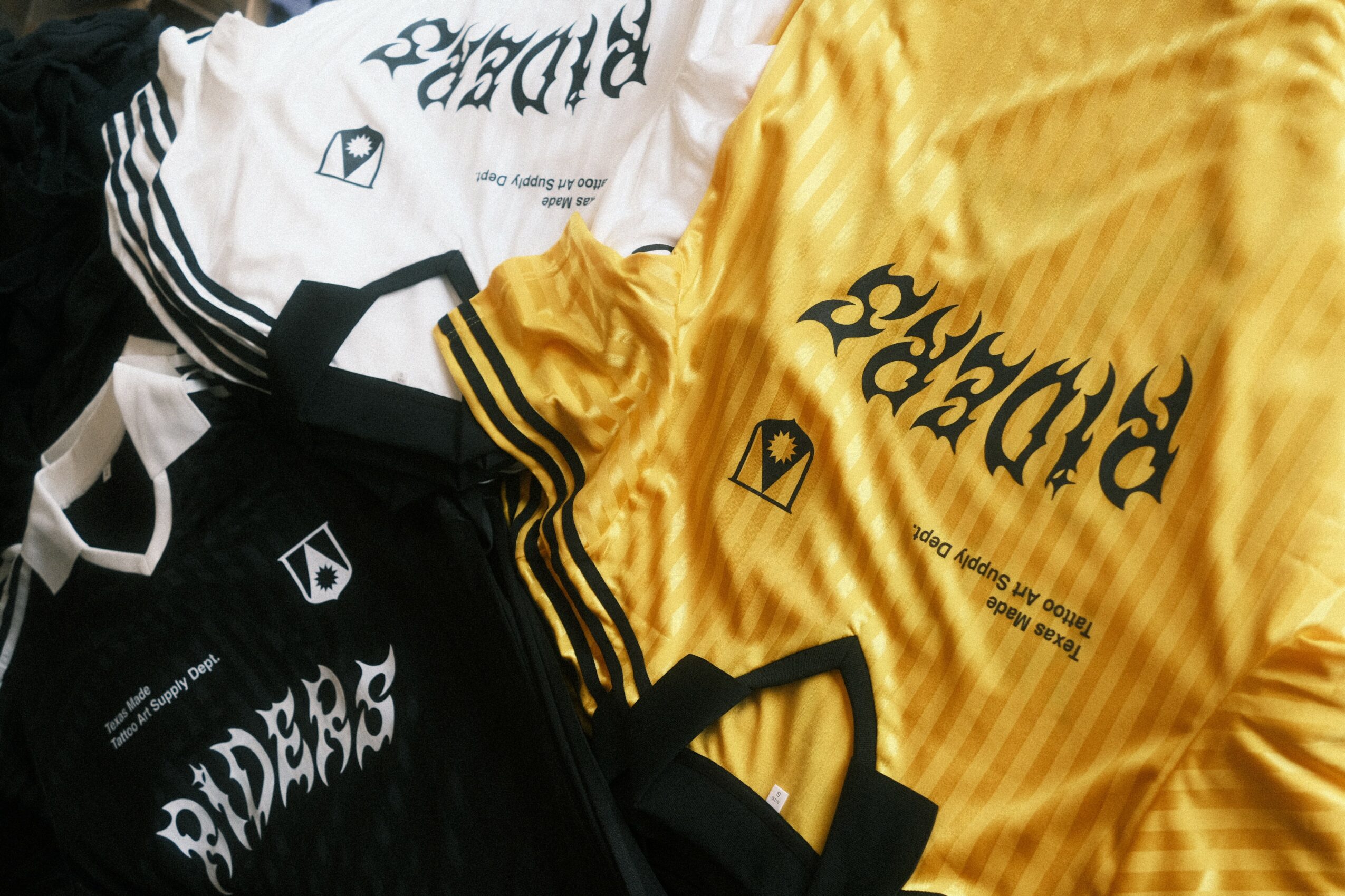 Two sports jerseys, one yellow and one black, with text and logos, laid flat on a surface.