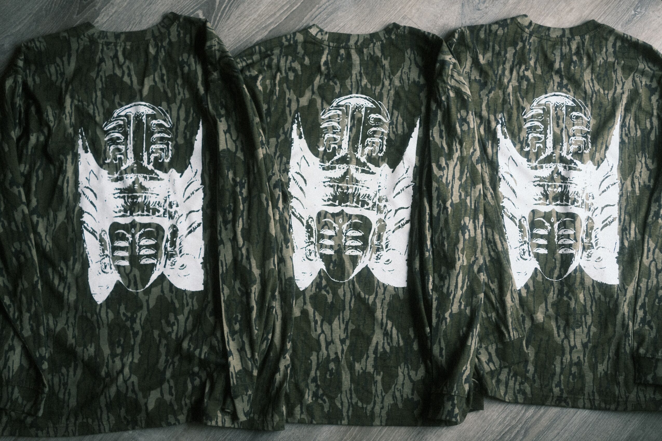 Three jackets with a white butterfly and face design on a dark, textured background.
