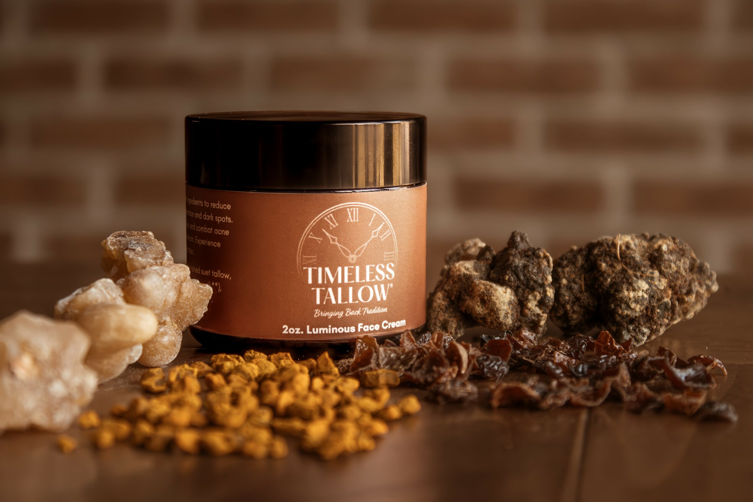 A jar labeled 'Timeless Tallow' surrounded by rocks and small yellow objects on a dark surface, brick wall background.