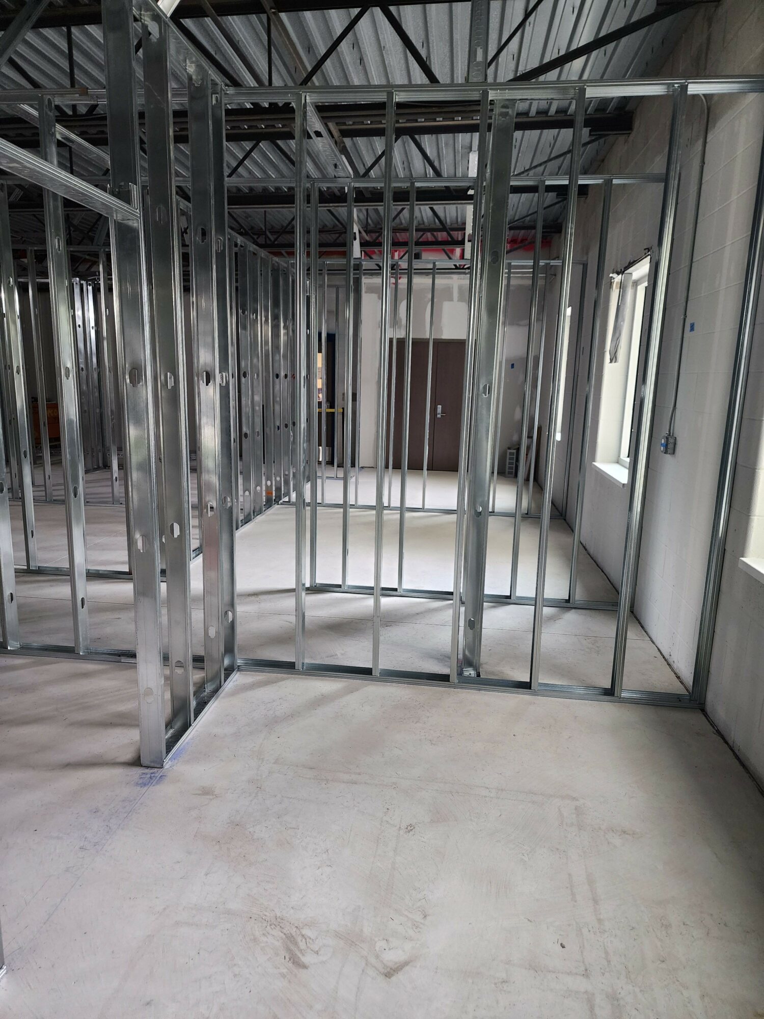 Metal shelving unit in a storage area with a concrete wall and ceiling light, viewed from the side.
