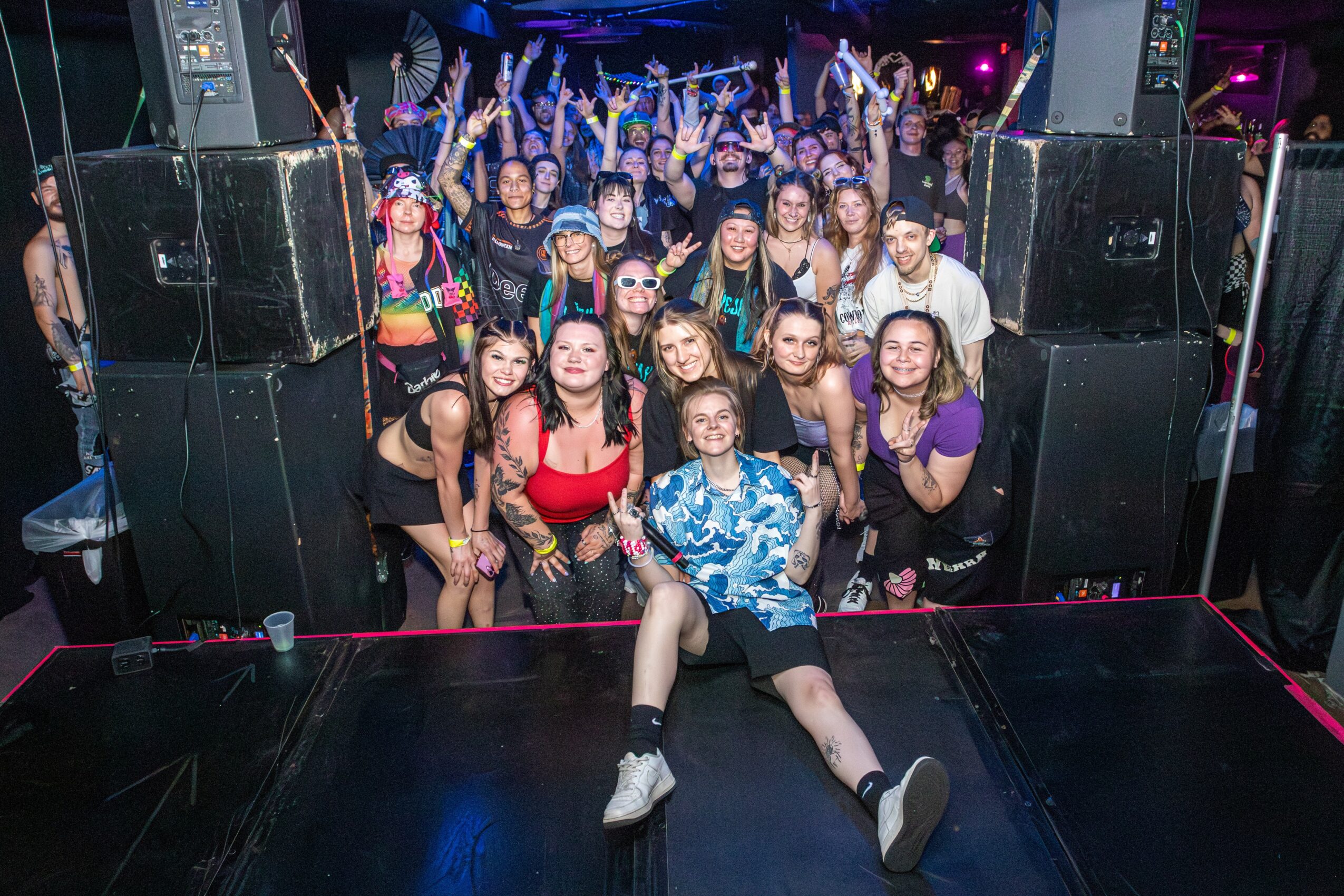 Group of people dancing and celebrating at a party or concert, with some raising hands and smiling.
