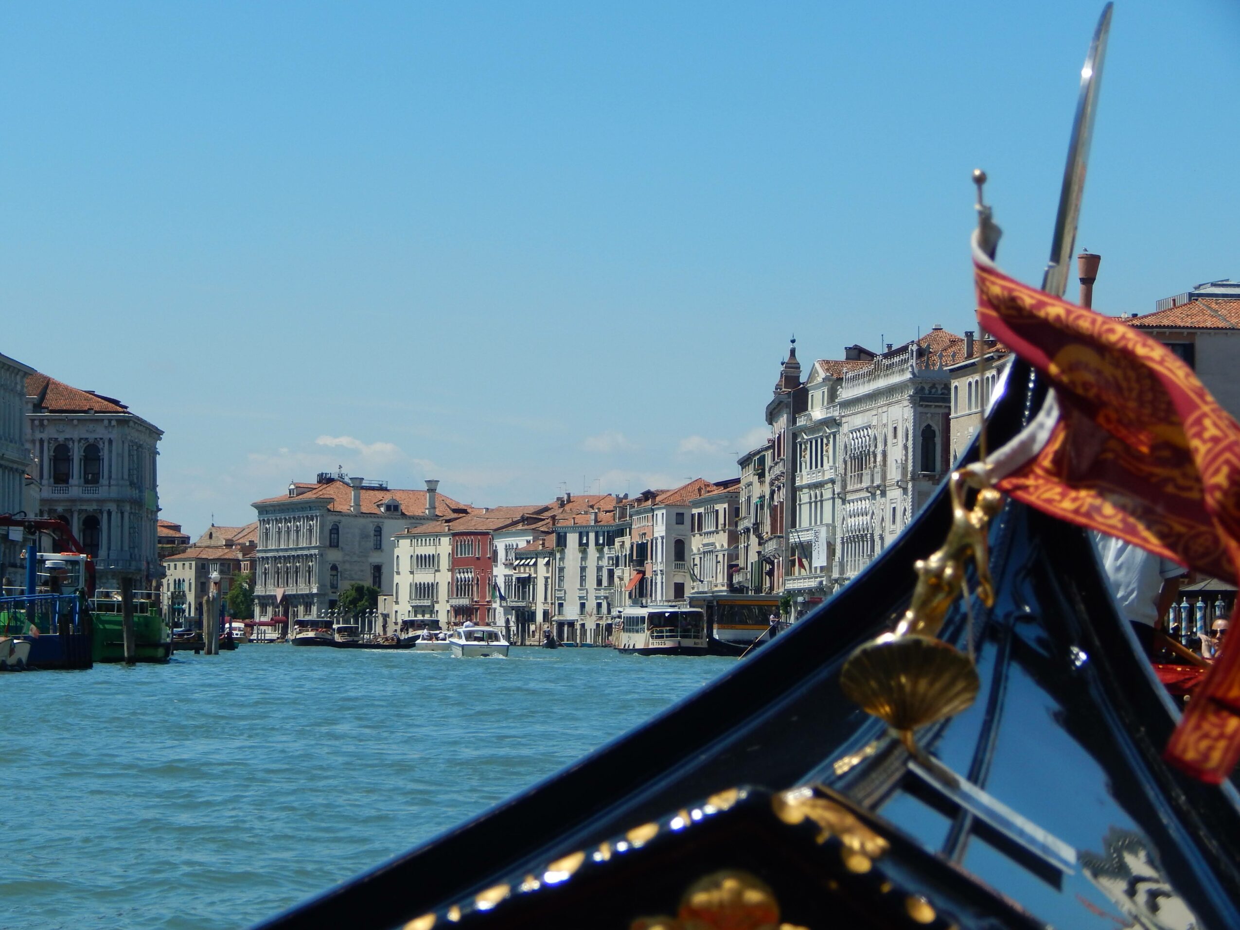 Gondola with decorative red fabric on waterway with historic buildings in background
